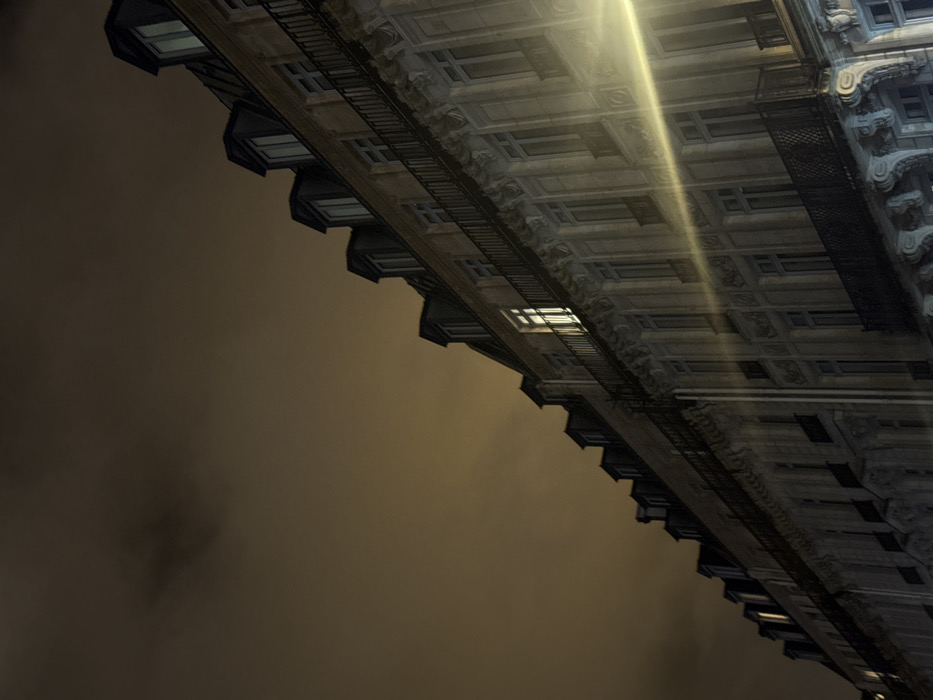 An angled perspective of a building at night. The facade features ornate detailing, rows of windows, and fire escapes. Yellowish clouds fill the sky behind the building, creating a hazy backdrop. A vertical streak of light illuminates the upper portion of the building's exterior.