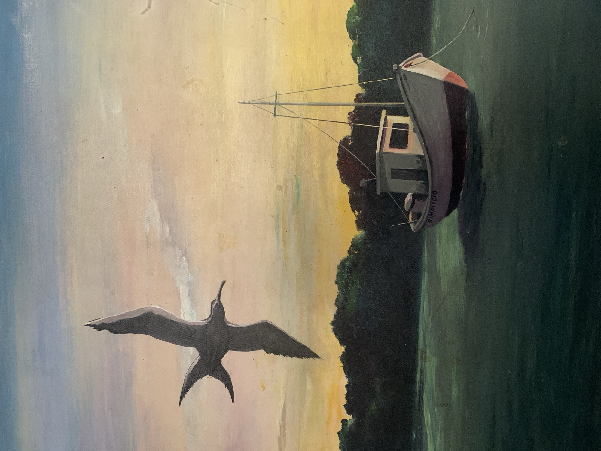 Oil painting featuring a frigatebird in flight. The bird is centrally located, wings spread, above an impressionistic body of water reflecting sky and bordering a dark shoreline. A weathered fishing boat, painted in grays and white with red accents, is moored near the shore. The boat's name, "SIMPLICIO," is visible on its hull. The sky transitions from light blue to yellow and peach tones, suggesting either sunrise or sunset. The overall composition evokes a sense of tranquility and the environment seems to be on the banks of the river of Santa Ana, Venezuela.
