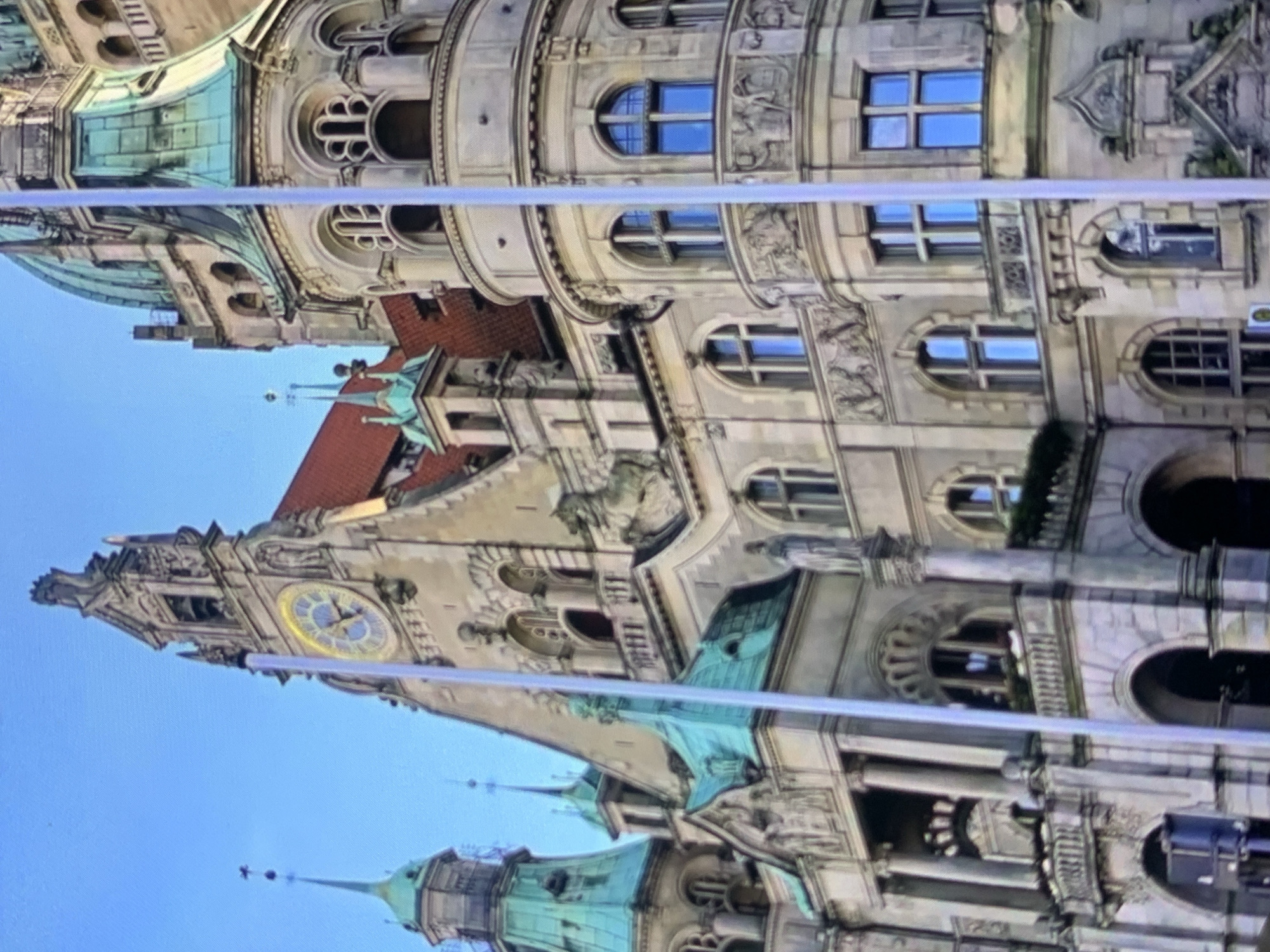 The image shows the New Town Hall of Hanover, Germany. The building is made of stone and features a large clock tower, several green copper-covered domes, and ornate architectural details. It is a sunny day with a clear blue sky. The image does not depict the city of Stavropol, Russia.