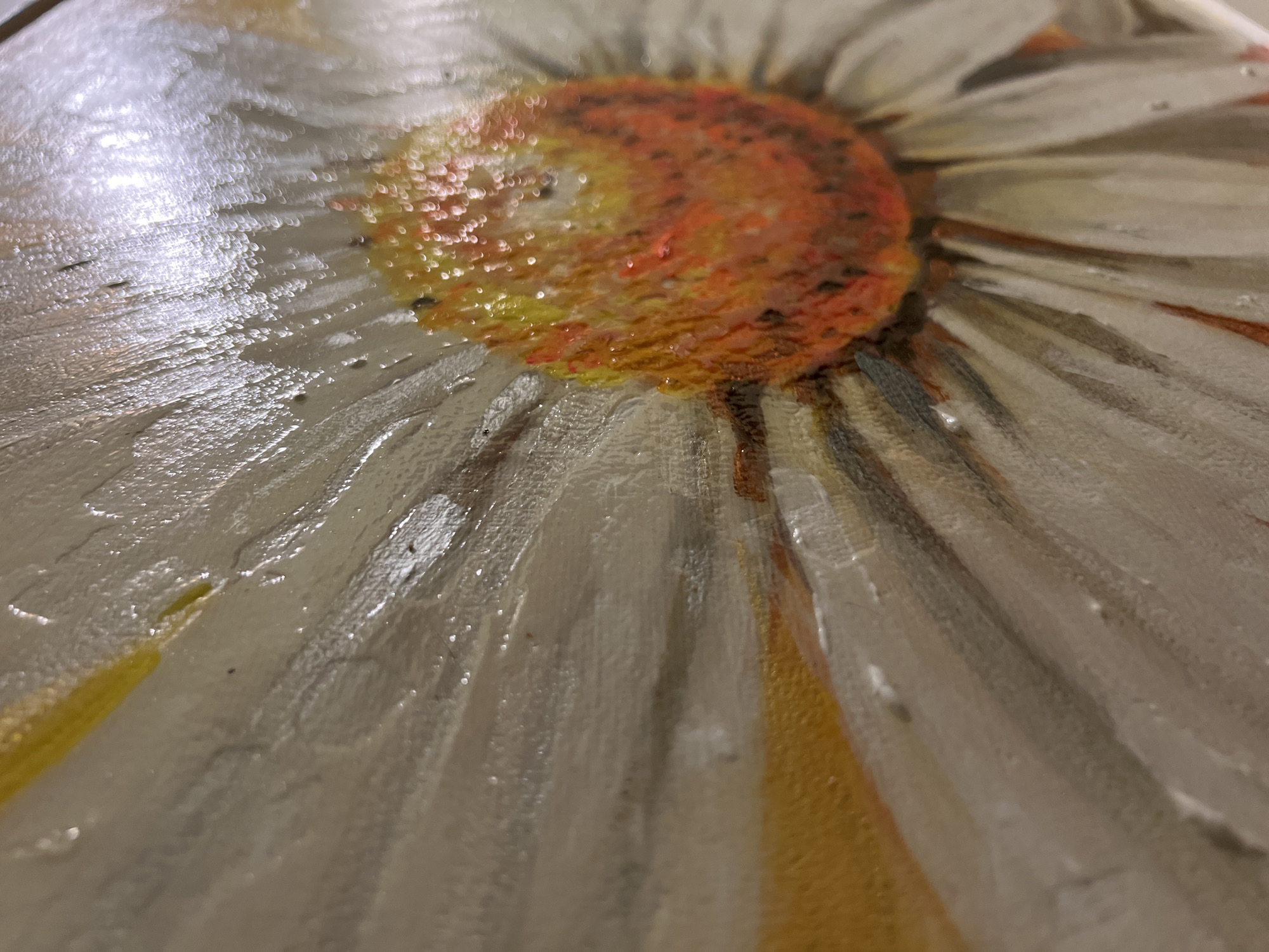 The image is a close-up, abstract photograph of a painting of a daisy. The center of the flower is depicted in shades of orange and yellow, with visible texture from the paint. The petals are painted in white and pale gray, radiating outwards. Some yellow is visible on the outer edges of some petals. The painting has a glossy finish, and the light reflects off its surface, creating bright highlights and obscuring some details. The focus is on the texture and color of the paint, rather than a clear depiction of the entire flower. The exact location in Minsk, Belarus, is not discernible from the image.