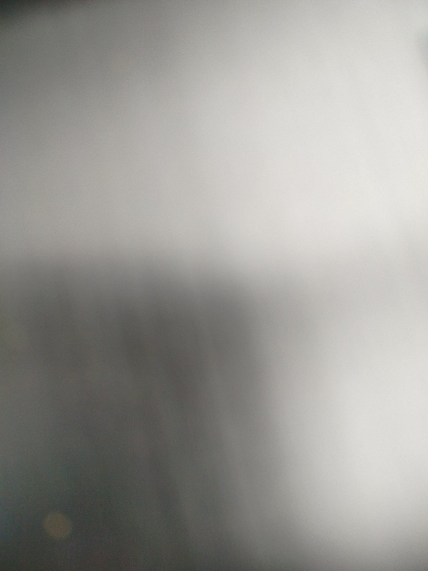 The image is a blurry, out-of-focus, gray-toned photograph. The upper portion of the image is lighter, fading into a darker gray towards the bottom. There is a slightly lighter area in the bottom-right corner. The location in Yerevan, Armenia is not discernible from the content of the picture. There are no people, subjects, objects, actions, or interactions visible in the image. The environment is indeterminate.