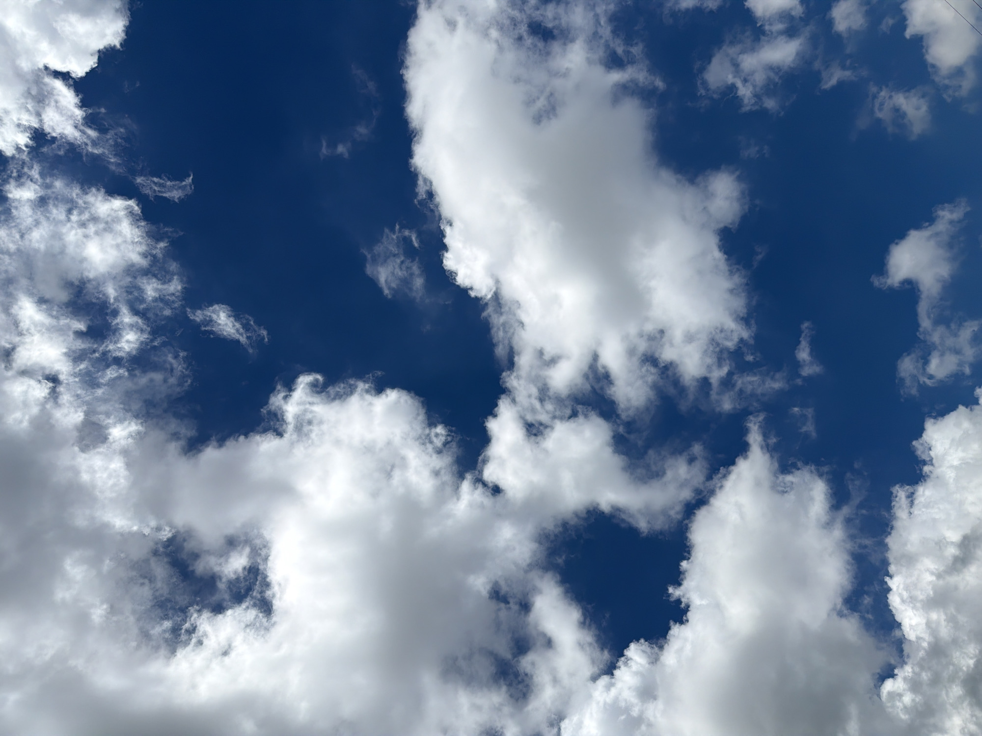 The image shows a sky filled with a mixture of white cumulus clouds and thinner, wispy clouds against a deep blue sky. There are no people, subjects, or objects visible in the frame. The scene is entirely natural, depicting a sky that could be seen from any open area in Davao City, Philippines, on a day with variable cloud cover.