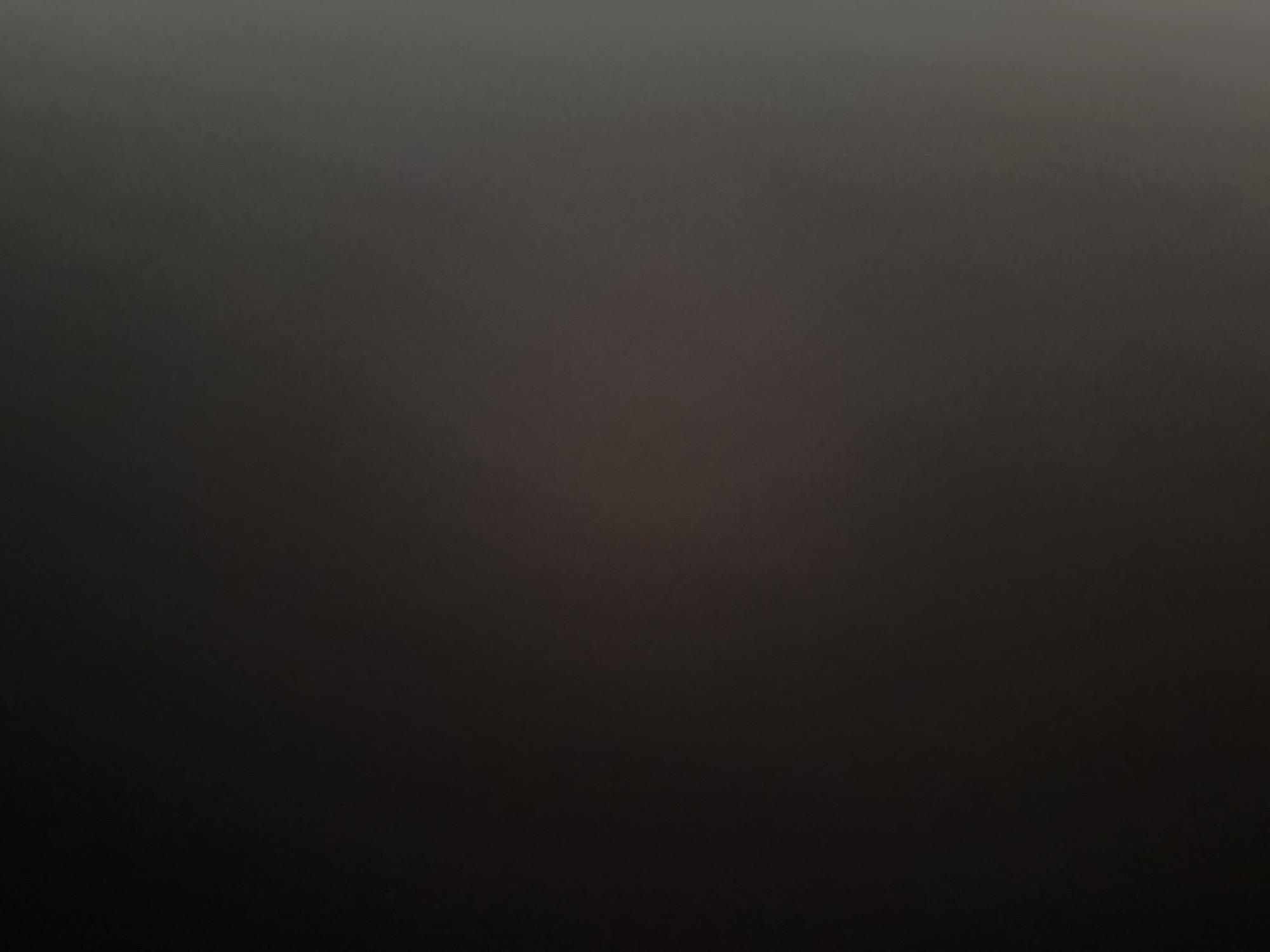 This media file is an abstract, dark, and blurry image with no discernible subjects, objects, scene, or setting. It is a homogeneous field of dark grays and blacks, with subtle variations in tone that suggest a slight gradient or soft lighting. There is no activity or event taking place, nor are there any notable details like time of day, weather, location cues, or emotions. No text is visible in the image. The image appears to be a photographic representation of a very dark, out-of-focus surface or environment.
