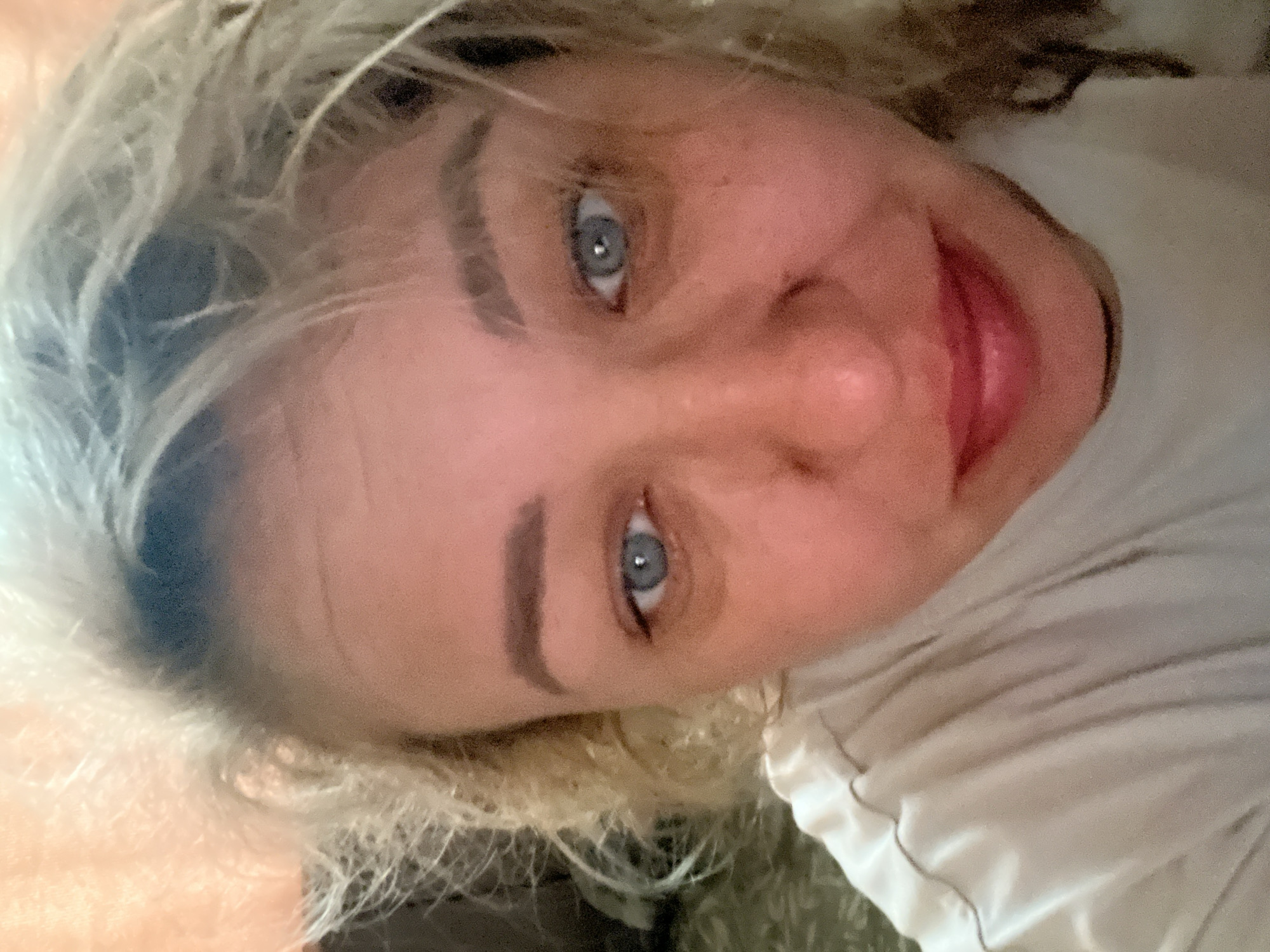 A close-up, slightly rotated portrait of a fair-skinned woman with light-colored hair and blue eyes. She is wearing a white t-shirt. The background is out of focus, providing minimal environmental context. There is no evidence to suggest that this image was taken in Chaikovsky, Russia, or any specific location.