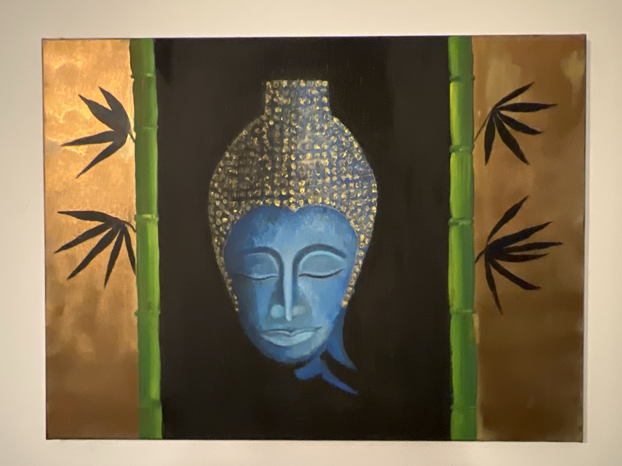 The image shows a painting featuring a blue Buddha head in the center, set against a black background. On either side of the black central area are green bamboo stalks and golden-brown areas with black leaf-like shapes. The painting appears to be mounted on a wall. The image does not depict Baošići, Montenegro, or provide information related to a specific location.