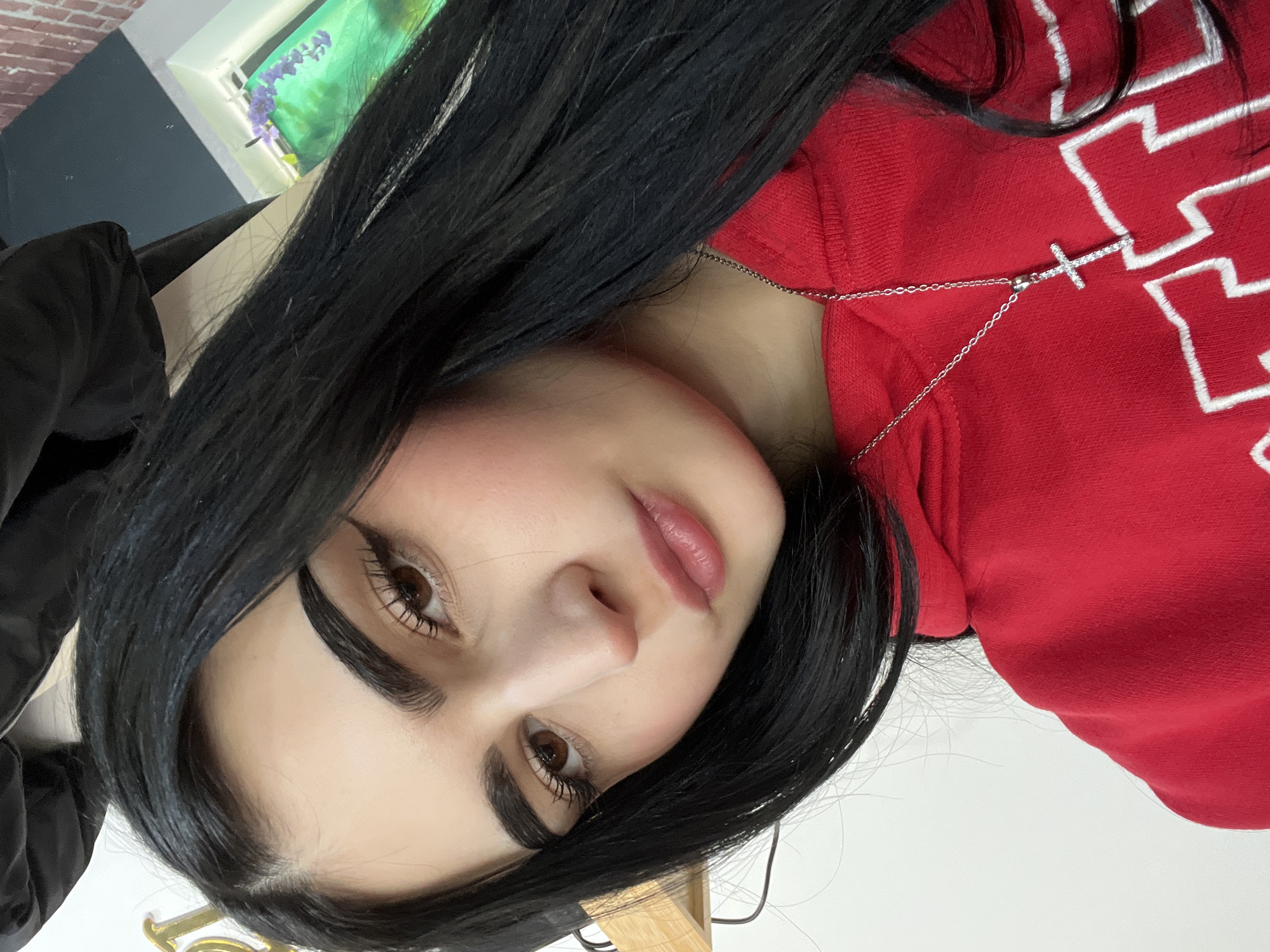 A portrait of a woman with long, black hair and brown eyes is presented. She wears a red hoodie with white lettering. A silver necklace with a cross pendant rests on her collarbone. The location of Burgas, Bulgaria is not discernible from the provided image.
