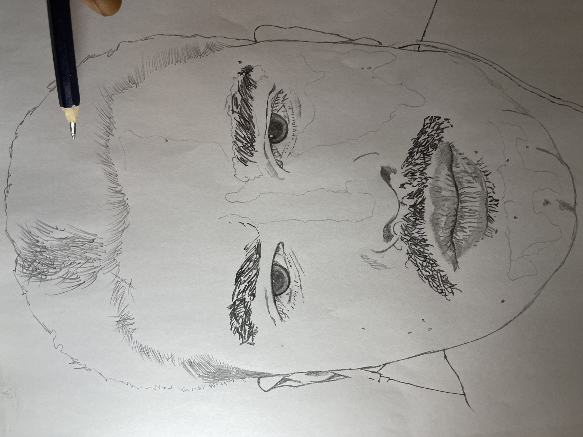 The image displays a close-up, top-down perspective of a partially completed pencil sketch of a human head on white paper, located in Jos, Nigeria. The central subject is a front-facing portrait, rendered in graphite, featuring a male-presenting individual with dark, prominent eyebrows, distinct eyes with visible pupils, a well-defined dark mustache, and shaded lips. Lightly sketched hair is visible on the top and sides of the head. Faint grid lines or construction marks are discernible across the face, suggesting a structured drawing process. A dark-colored pencil with a sharpened lead is positioned at the top right, held by a visible light-skinned hand, indicating the active creation or a pause in the sketching process. The drawing exhibits varying levels of completion, with facial features like the mustache, eyes, and eyebrows significantly more detailed than the forehead, nose, or jawline, which remain largely outlined.