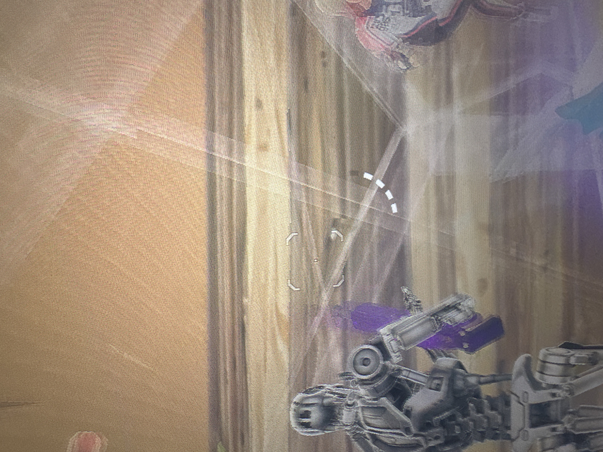 This is a screenshot from a video game. It depicts two robotic characters in a sandy, desert-like environment. The character on the left is a humanoid robot with a metallic gray finish, a detailed chest piece, and what appears to be a weapon or tool in its left hand. The robot on the right is partially visible and appears to be wearing red and white armor. There are glowing, translucent lines and target reticles superimposed on the image, indicating gameplay elements. The background is a textured, sandy expanse with horizontal bands of color that suggest distance or terrain features. There is no indication of a city or any specific location like Bezden, Bulgaria.