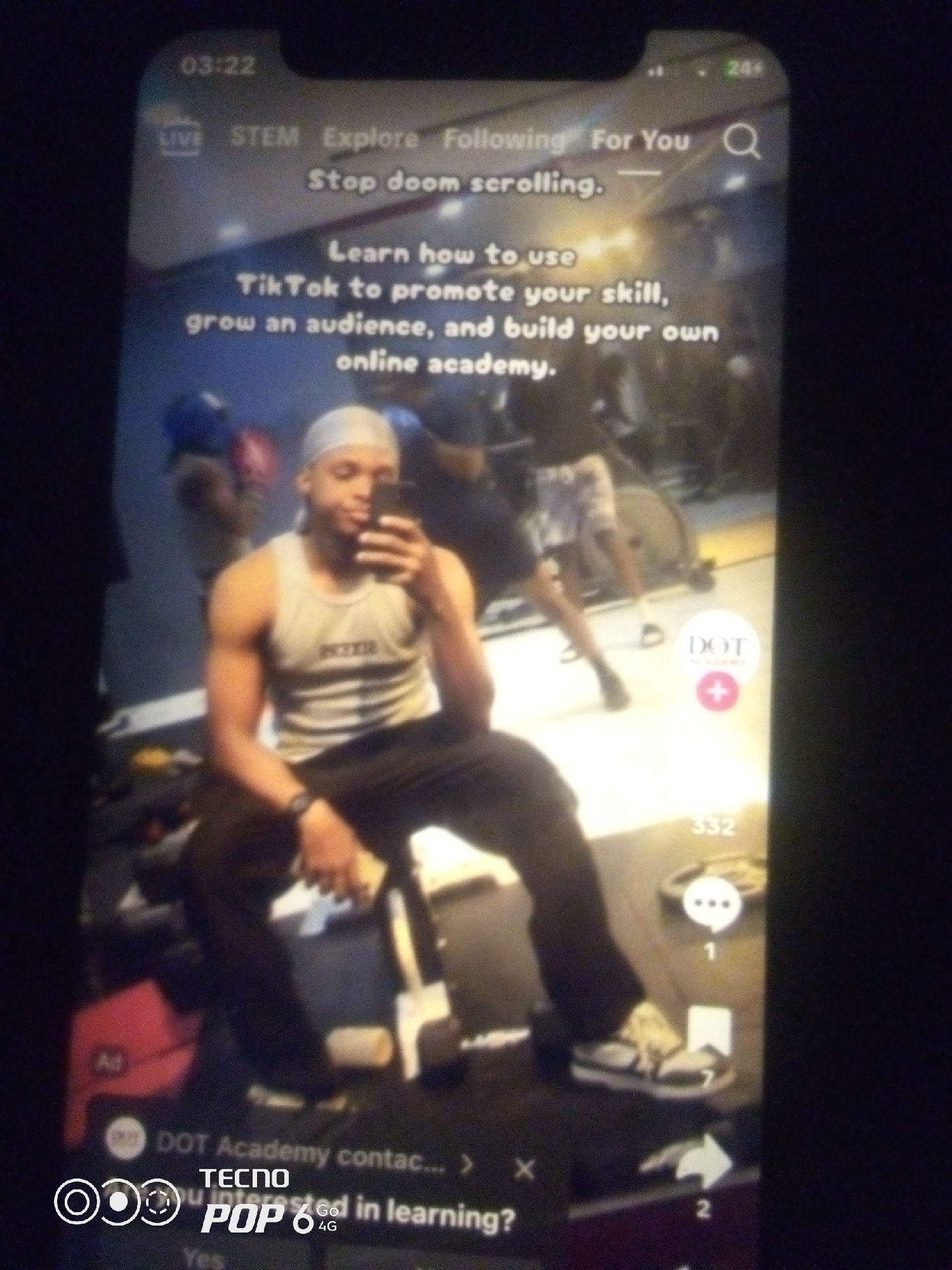 The image shows a TikTok video playing on a smartphone. The video features a man in a gym, wearing a durag, a tank top, and dark pants. He is holding a smartphone and appears to be taking a selfie. Text overlays on the video promote learning how to use TikTok to grow an audience and build an online academy. The timestamp on the phone reads "03:22". The bottom of the screen displays "TECNO POP 6 4G" and other interface elements related to the TikTok app. The background is a gym setting with exercise equipment visible. There is no information in the image to suggest a specific location in Howayi, Nigeria.
