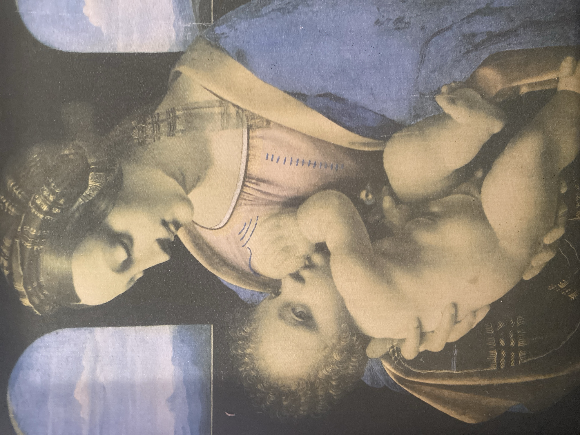 The image is a reproduction of a Renaissance painting, likely a depiction of the Virgin Mary and the Christ Child. The subjects are a woman and a baby. The woman, presumed to be Mary, is shown in profile, her head tilted downwards towards the baby. She has dark, curly hair styled with some form of head covering or elaborate braiding. Her expression is gentle and serene. The baby, positioned in her arms, is facing the viewer. He is nude and appears to be reaching for or holding his mother's finger or face. The baby has curly hair and a soft, cherubic appearance.
They are dressed in garments typical of the era. The woman wears a pale pink garment with vertical blue stitching detail, and a blue drape or robe is visible. The baby is cradled by the woman's arms and fabric. The background is dark, with hints of architectural elements or drapery. On the left side of the image, there is a section that appears to be a window or archway revealing a sky with clouds, painted in shades of blue and white, suggesting an indoor setting with a view to the outside. The overall mood conveyed is one of tender maternal love and devotion. There is no visible text within the image. The context of Brest, Belarus, is external information and not directly evident from the artwork itself.