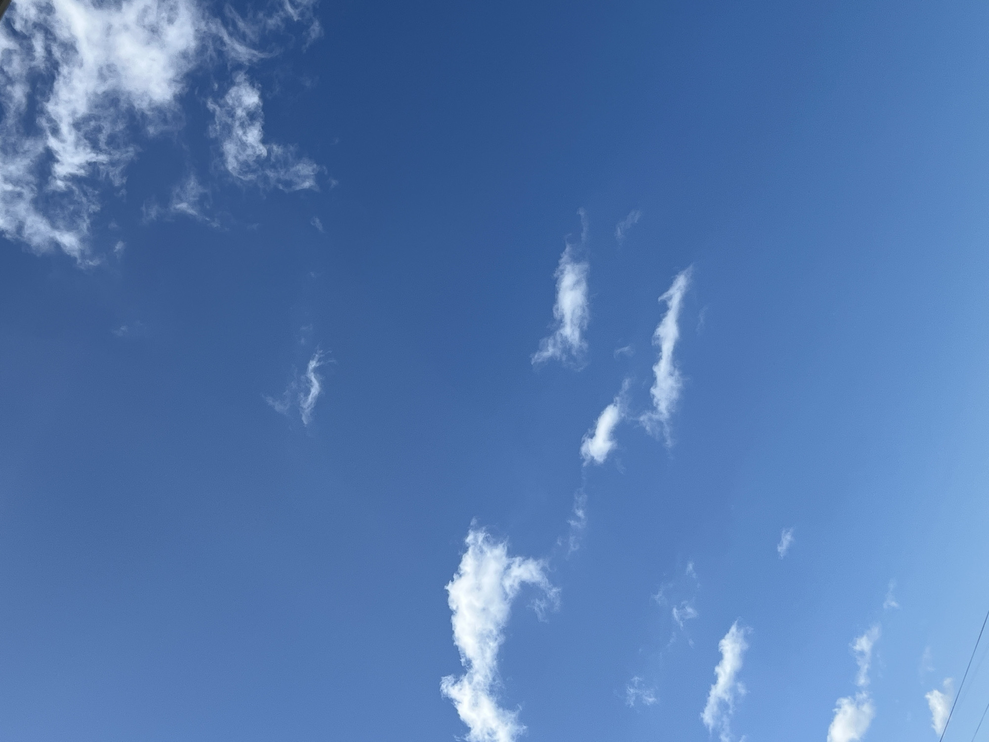 A clear blue sky with scattered white clouds. In the lower left corner, a faint horizontal line, likely a power line, is visible. There are no people or discernible objects in the image. The image appears to be taken outdoors, possibly in Tolyatti, Russia, given the request.