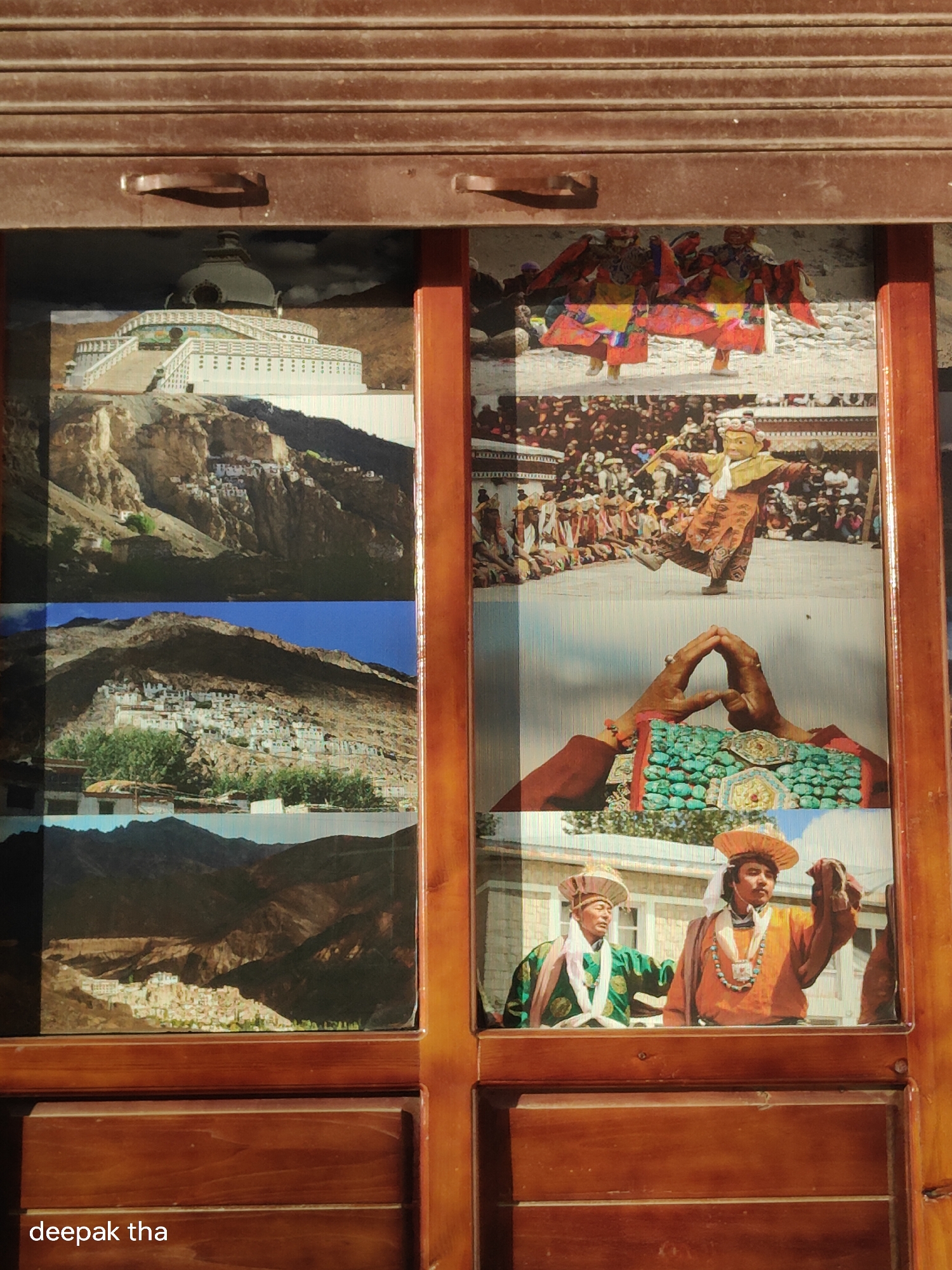 The image displays a montage of photographs framed within a wooden structure. The top left photograph shows the Shanti Stupa in Leh, India, a prominent Buddhist monument situated on a hilltop. The remaining photographs depict various cultural scenes, including people in traditional attire, possibly participating in a festival or ceremony, and landscapes of mountainous regions. The bottom left corner of the image contains text that reads "deepak tha". The overall presentation suggests a decorative display, perhaps in a shop or a home, showcasing aspects of Leh's culture and environment.