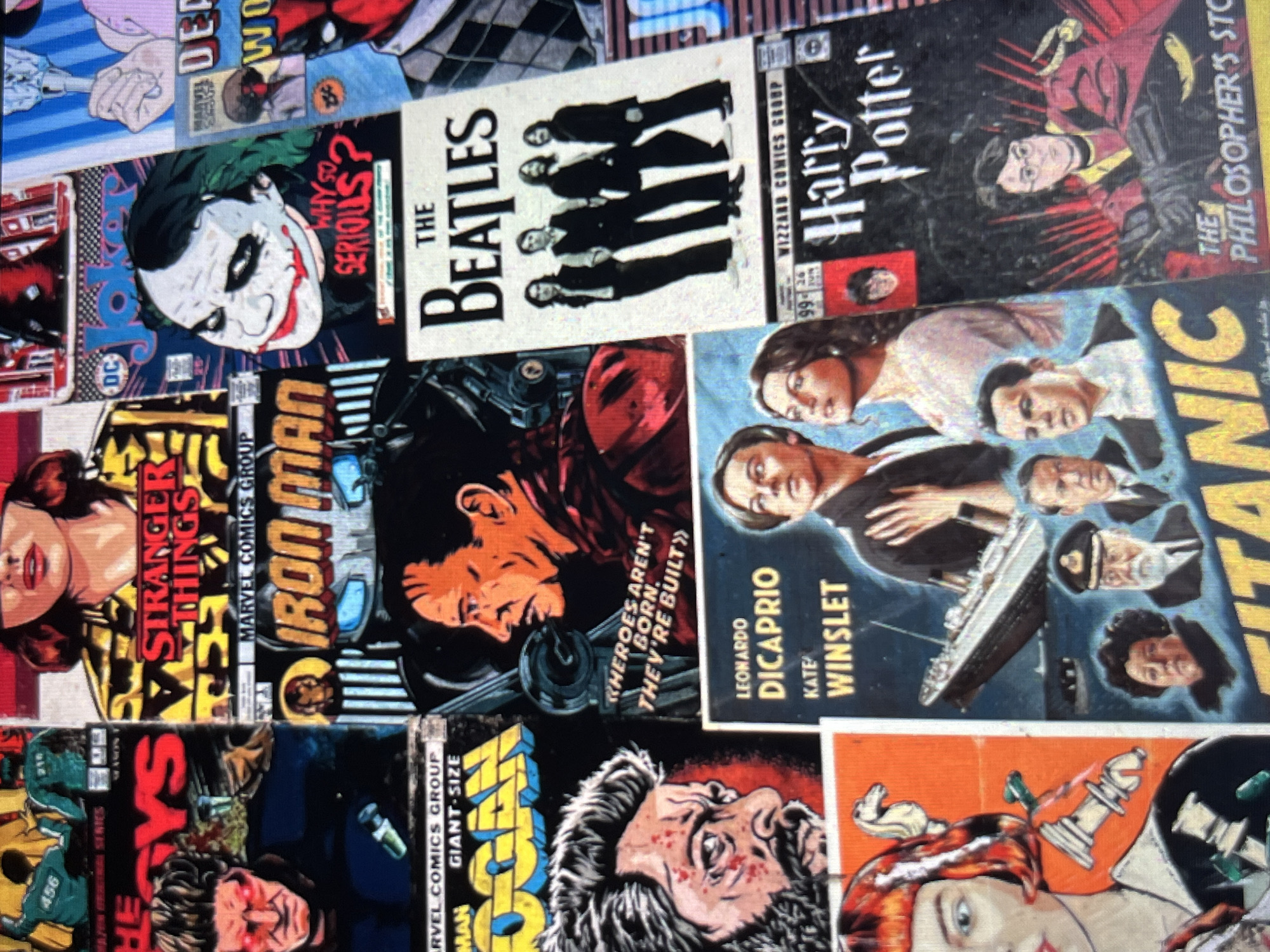The image is a close-up of a collection of stacked comic book covers. Titles include "The Joker: Why So Serious?", "The Beatles", "Harry Potter and the Philosopher's Stone", "Titanic" with Leonardo DiCaprio and Kate Winslet, "Iron Man", "Stranger Things", and "Wolverine/Logan". The covers are in a somewhat disorganized arrangement, with some tilted or partially obscured. The setting or location, Tinaquillo, Venezuela, is not evident from the visual details of the image itself.