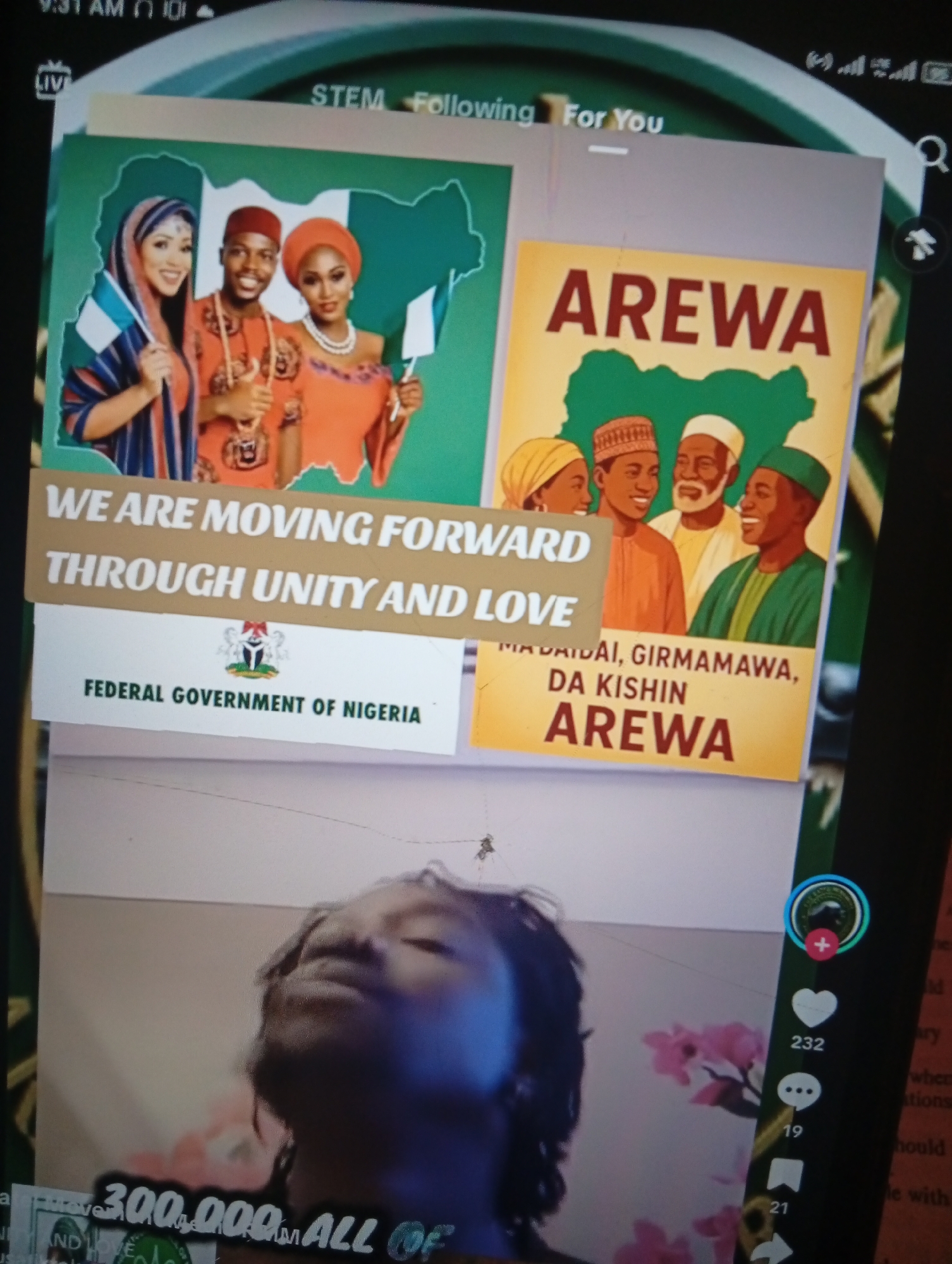 The image is a screenshot of a digital display, possibly a mobile phone or computer screen. The foreground shows a person's face in the lower half of the frame, looking upwards with their eyes closed and a slight smile. The background features two framed posters or images. The left poster displays three individuals, two women and one man, dressed in traditional Nigerian attire and holding Nigerian flags. Behind them is a green outline of Nigeria. The text on this poster reads: "WE ARE MOVING FORWARD THROUGH UNITY AND LOVE" and "FEDERAL GOVERNMENT OF NIGERIA". The right poster features a group of four people, men and women, also in traditional clothing, with a yellow background. The prominent text on this poster reads "AREWA". A smaller text above "AREWA" appears to be in a local Nigerian language. The overall context suggests a celebration of Nigerian culture and unity, possibly related to the Arewa region. There is no visible indication of the city of Zongoma Kyari, Nigeria, within the image.