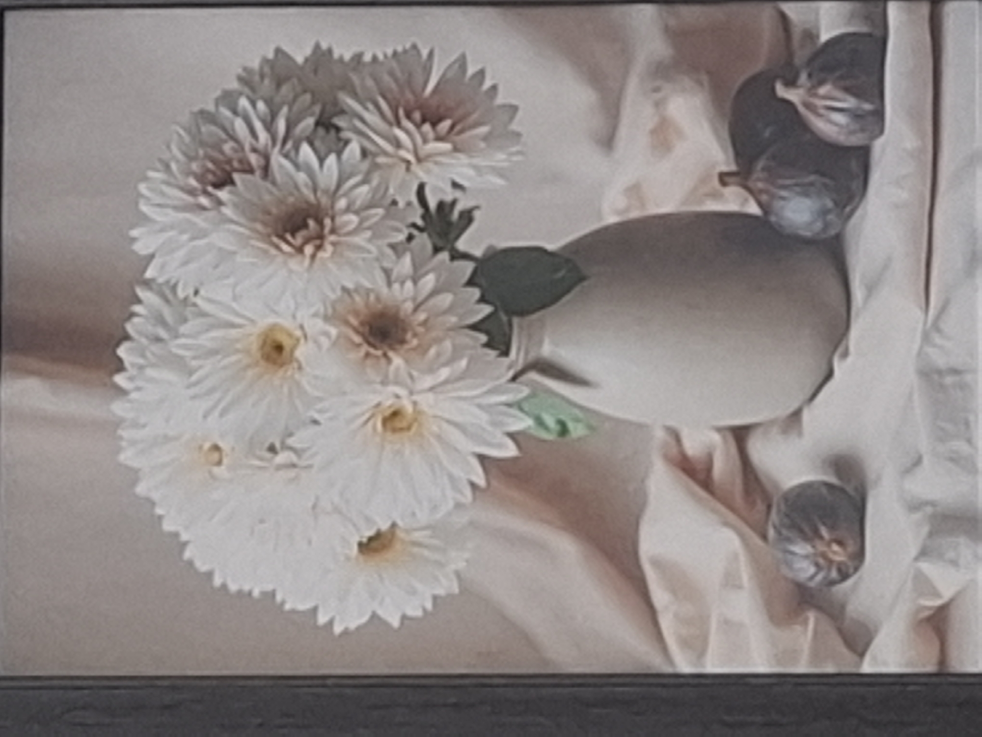 The image is a still life painting of a bouquet of white chrysanthemums in a light-colored vase, placed on a draped fabric. To the left of the vase, there are three figs arranged on the fabric. The background is a soft, neutral tone. The painting is framed by a dark border. The location in the city of Almaty, Kazakhstan is not discernible from the image.