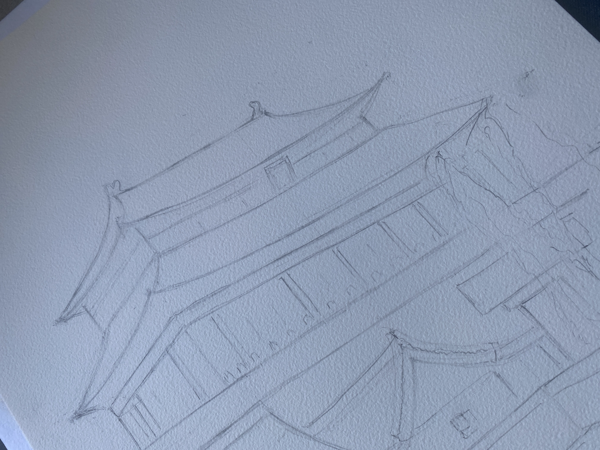 The image is a close-up, overhead pencil sketch on textured white paper, depicting an architectural study of what appears to be a traditional building with distinct rooflines and tiered structures. The sketch is very light, with visible pencil lines and some cross-hatching to suggest depth or texture. The architectural style features prominent, upward-curving roof eaves, suggesting influences from East Asian or possibly certain historical European styles. There are linear elements that could represent windows or decorative panels on the building's facade. The sketch is incomplete, with unfinished sections and loose lines, indicating it is a work in progress. The overall impression is one of an architectural draft or a detailed study of a specific building's form. There are no people, animals, or recognizable elements of the city of Budva, Montenegro, present in this image.