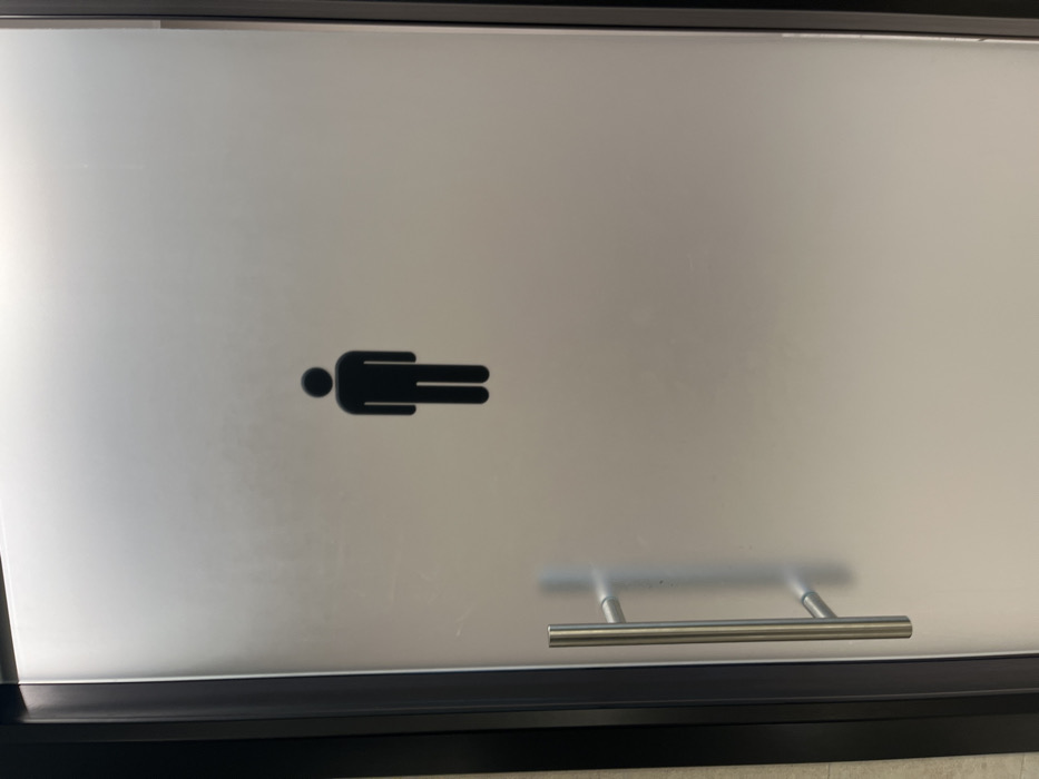 The image shows a frosted glass door, likely for a restroom, located in Dorno, Italy. A prominent black, stylized male figure icon is adhered to the upper-left to central portion of the frosted glass. This pictogram, which appears to be lying on its left side, features a circular head and a rectangular body with two parallel lines forming the legs, commonly used to designate a men's facility.
The door is framed in black material, and a brushed metal, horizontal bar-style handle is visible on the lower right side, attached by two vertical supports. The frosted nature of the glass provides privacy, obscuring the view behind the door while still allowing light to pass through. The lighting suggests an indoor setting, likely during the day or under artificial light. There is no visible activity taking place, and no additional text or specific location cues are present beyond the door and its handle. The overall design implies a functional and modern aesthetic, typically found in public or commercial buildings.