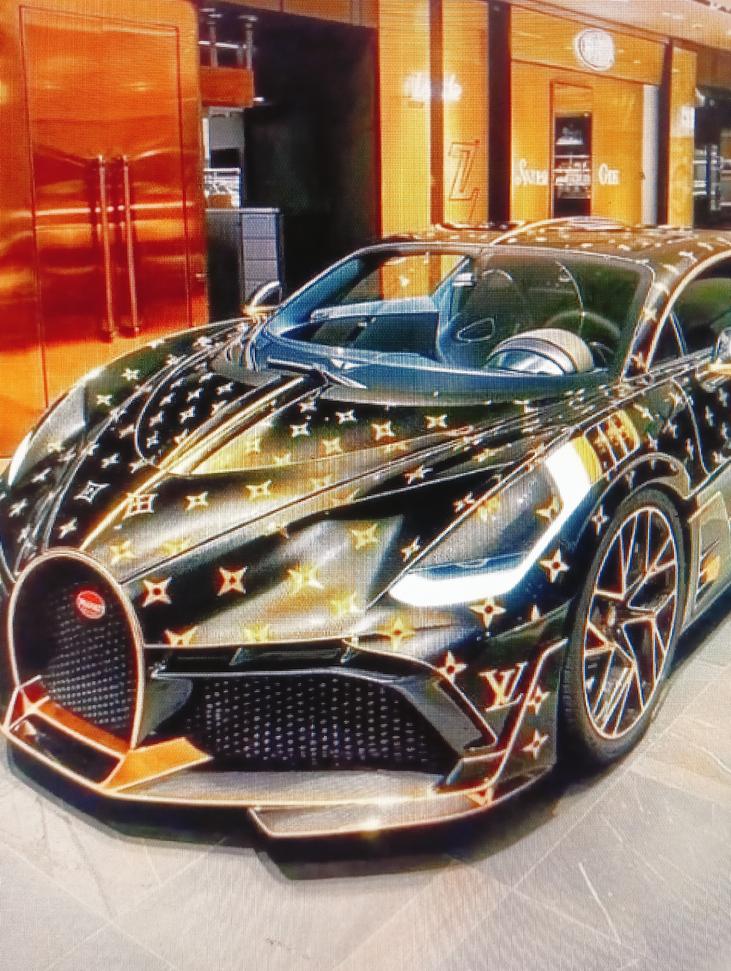 A black Bugatti Chiron is parked in front of a store with an orange facade. The car is covered in a Louis Vuitton monogram pattern. The store has large windows and is lit with bright lights. The car's headlights are on. The ground is tiled.