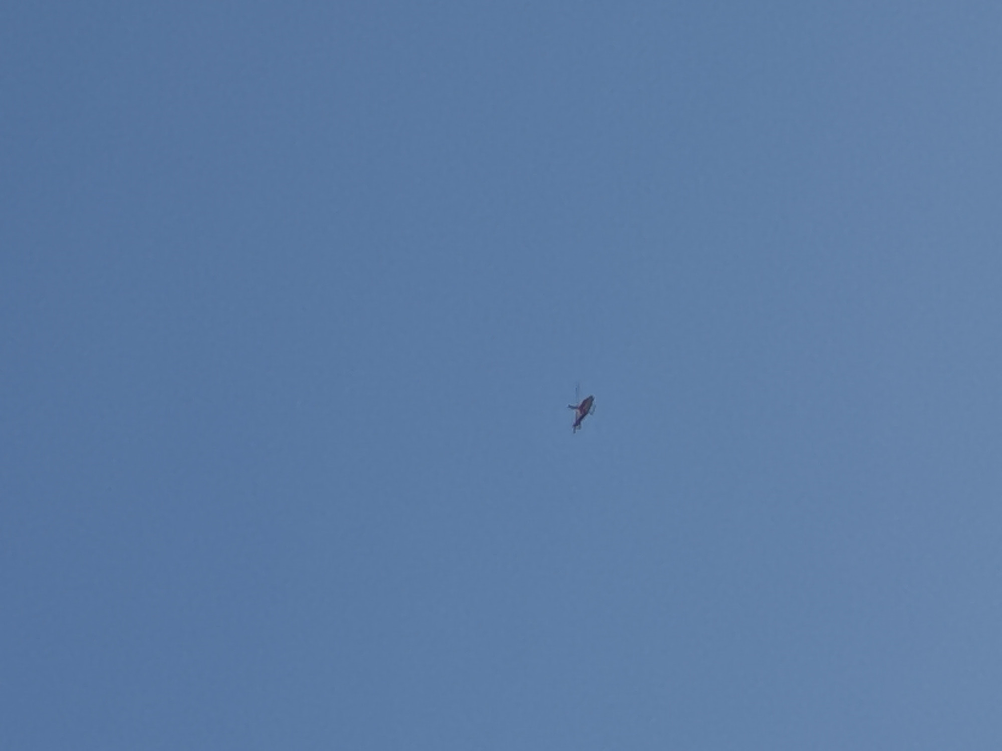A helicopter is in flight against a clear blue sky. The location is not identifiable from the provided image.