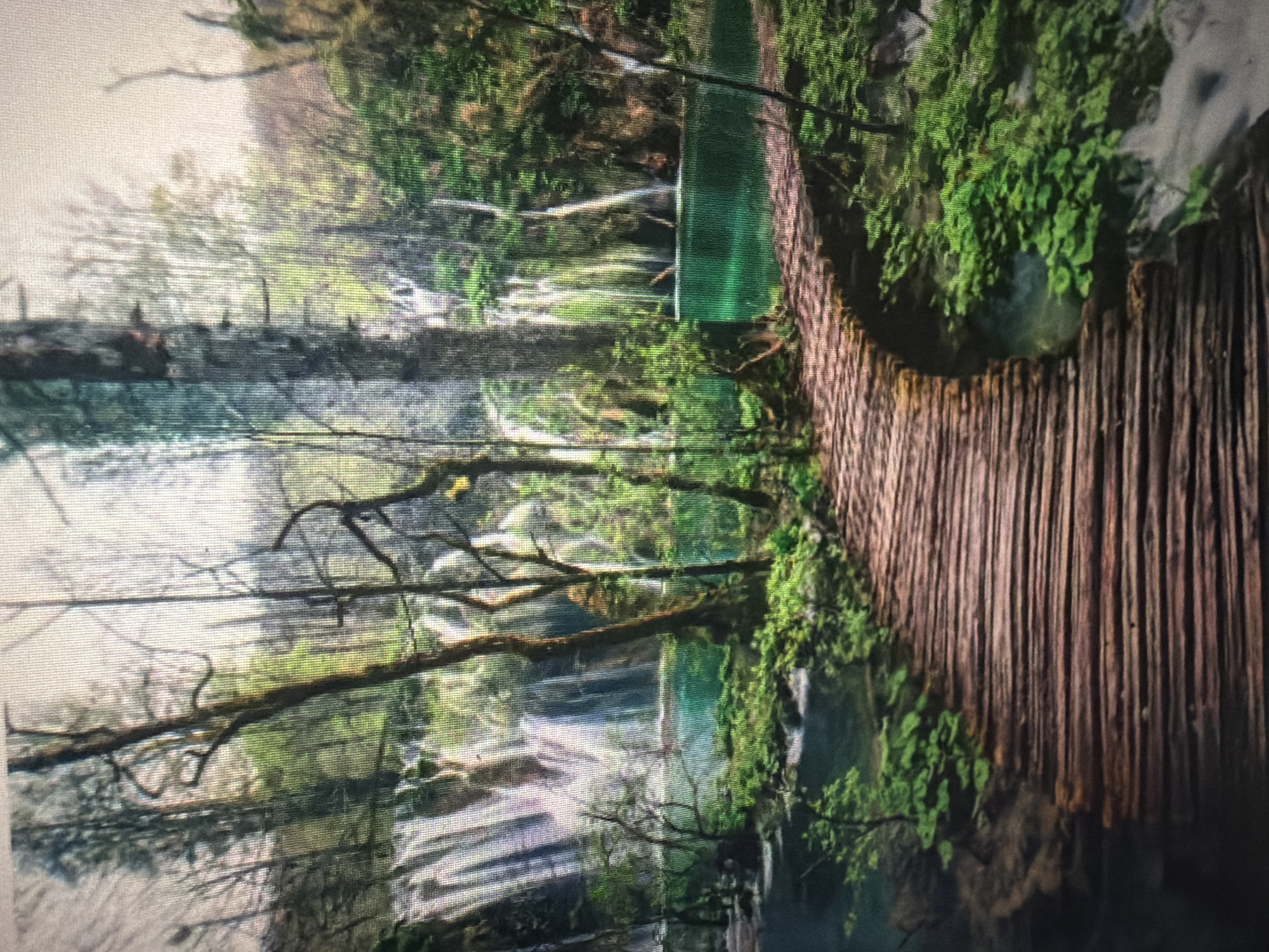 The image depicts a serene natural landscape featuring a wooden boardwalk winding through a lush forest. Cascading waterfalls and a vibrant turquoise body of water dominate the background, surrounded by dense green foliage and tall trees. The boardwalk, made of weathered wooden planks, curves gently, inviting the viewer into the scene. The overall impression is one of natural beauty and tranquility.
However, this image is not located in Baan Mae Nam, Thailand. It is a photograph of Plitvice Lakes National Park in Croatia, a UNESCO World Heritage site renowned for its stunning waterfalls and interconnected lakes.