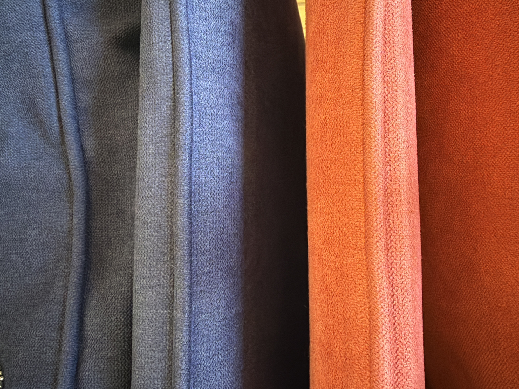 The image shows a close-up view of several pieces of soft fabric with a rough texture. The fabrics are in shades of blue and orange/brown. The fabrics are vertically arranged in the frame, forming a slightly wavy pattern. The image does not provide enough information to determine the location in Kazan, Russia or to include details about people, objects, actions, or interactions.