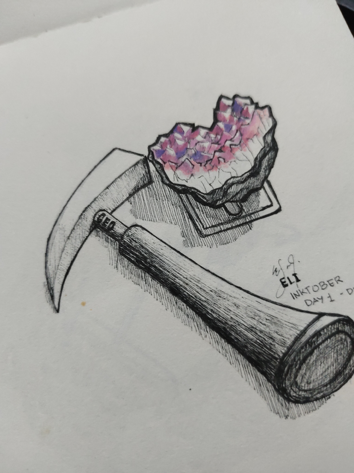 The image is a pen-and-ink drawing rendered on white paper, depicting a geological hammer and a crystal cluster with a stand. No specific real-world location in Davao City, Philippines, or elsewhere, is depicted within the drawing; it is a still-life representation on a blank white background.
The geological hammer is positioned diagonally from the upper left to the lower right of the frame. Its metallic head features a curved, pointed pick on the left and a broader, blunter striking face on the right, partially obscured by the crystal's stand. The handle, extending towards the lower right, is rendered with dark, parallel ink lines suggesting wood grain and texture. A shadow, indicated by cross-hatching, is cast beneath the hammer.
To the upper right of the hammer, a crystal cluster rests on a small, rectangular stand. The cluster has an irregular, jagged form composed of numerous small, faceted crystals. These crystals are colored in shades of pink and purple, with white areas serving as highlights. The stand beneath the crystals is also rendered in dark ink with cross-hatching for shading. A cast shadow is visible beneath the stand and crystal, also indicated by cross-hatching.
In the lower right quadrant of the image, handwritten text in black ink reads: "ELI", preceded by a swirling signature mark. Below "ELI", the word "INKTOBER" is written, followed by "DAY 1 - D".
The overall medium is predominantly black ink for outlines, shading (using cross-hatching), and text, with added pink and purple coloration on the crystal cluster. The background is the plain white surface of the paper. A small, faint yellowish smudge is visible on the paper to the left of the hammer's handle.