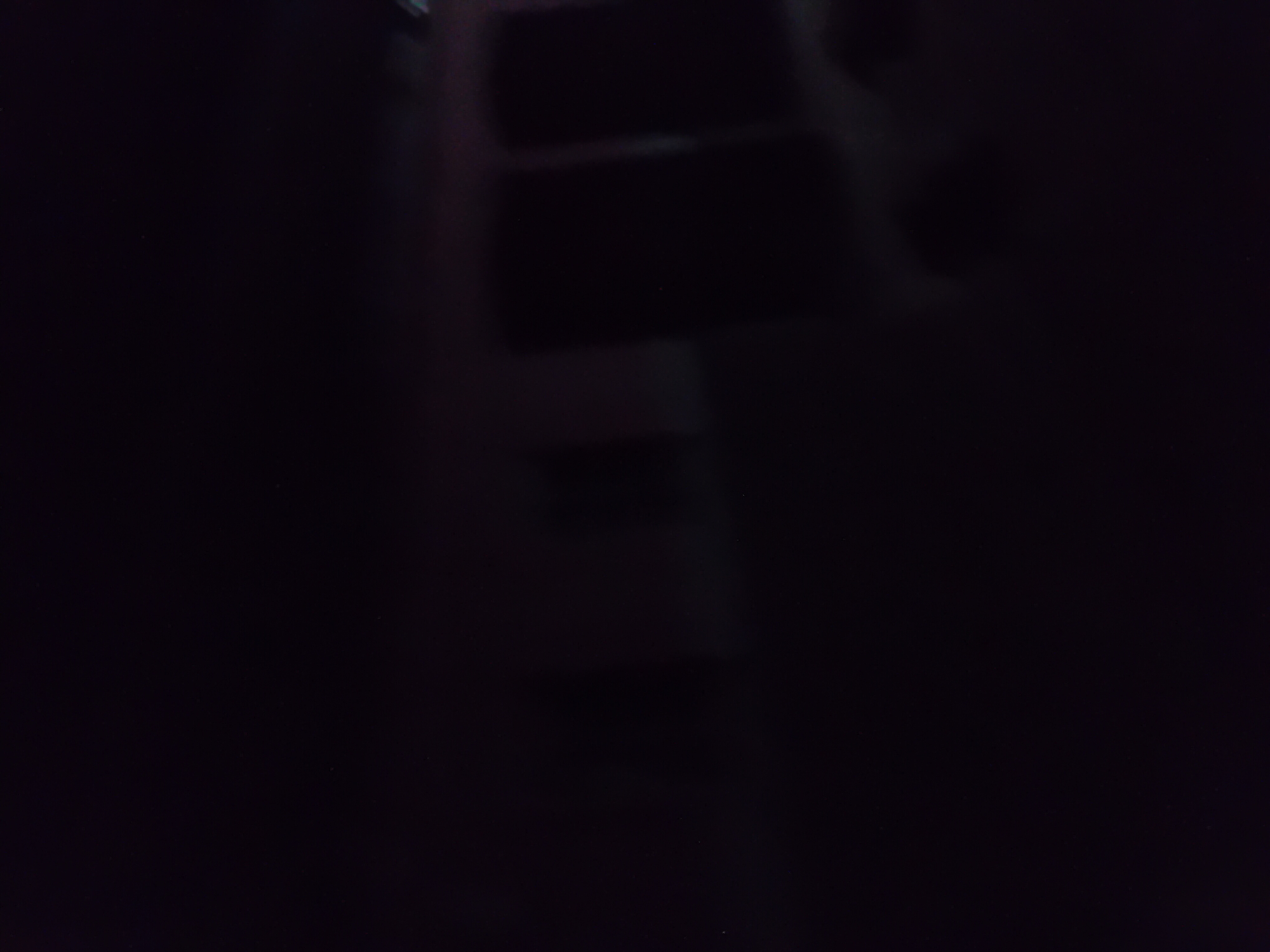The image is a dark, blurry photograph of what appears to be a building at night. There are some faint lights visible, suggesting interior lighting or external illumination. The building seems to have windows or large dark panels. The overall scene is indistinct due to low light and motion blur. Without additional context or clearer details, it is not possible to ascertain the specific location within Jauro Yinu, Nigeria, or identify any people, objects, or actions.