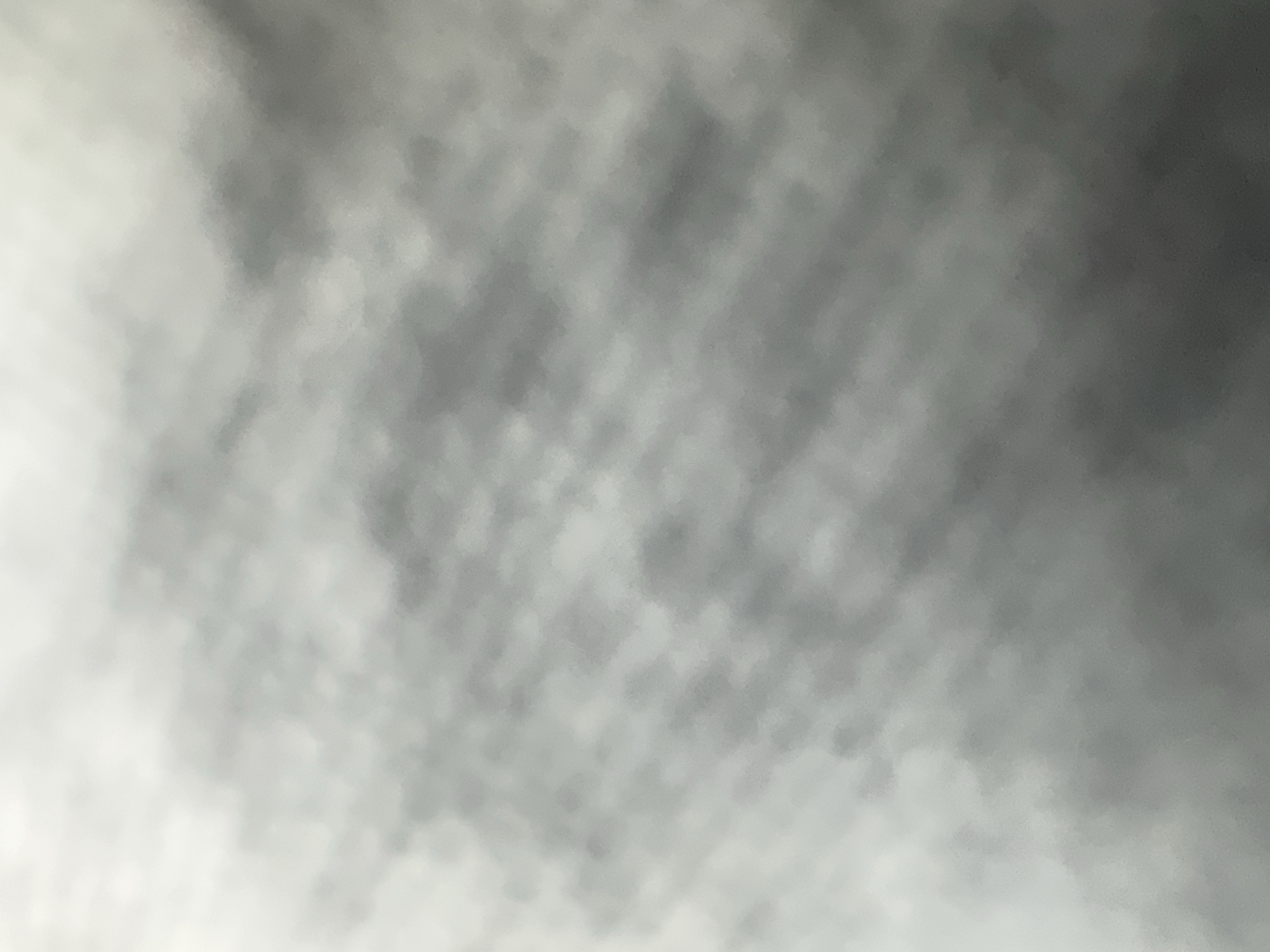 The image is a close-up, out-of-focus shot of a textured surface. It appears to be a fabric or paper with a woven or embossed pattern, predominantly in shades of grey and white. The lighting is diffuse, creating soft shadows and highlights across the surface, giving it a slightly mottled or cloudy appearance. There are no discernible objects, people, or specific locations identifiable within the frame. The lack of detail and sharp focus makes it impossible to determine its context, including any relation to Belgrade, Serbia.