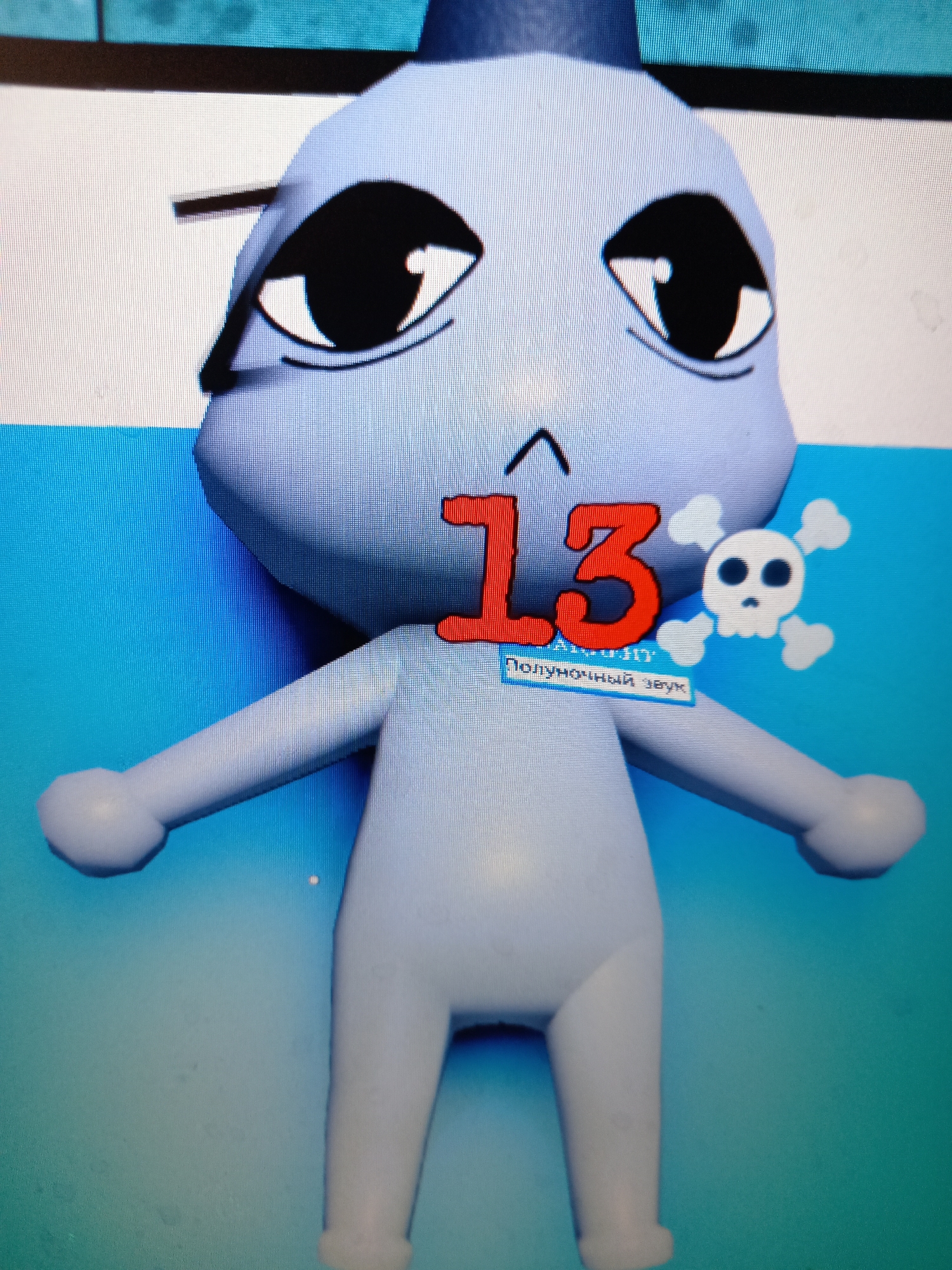 The image shows a 3D render of a light blue, cartoonish character with large black eyes. The character is wearing a dark blue hat and has a small, upside-down caret symbol above its nose. A large, red number "13" is displayed prominently on the character's chest. To the right of the number 13 is a white skull and crossbones icon. Below the number 13, a small rectangular box contains the Russian text "Полуночный звук". The background is a split of white and light blue. There is no discernible connection to the city of Rudny, Kazakhstan.