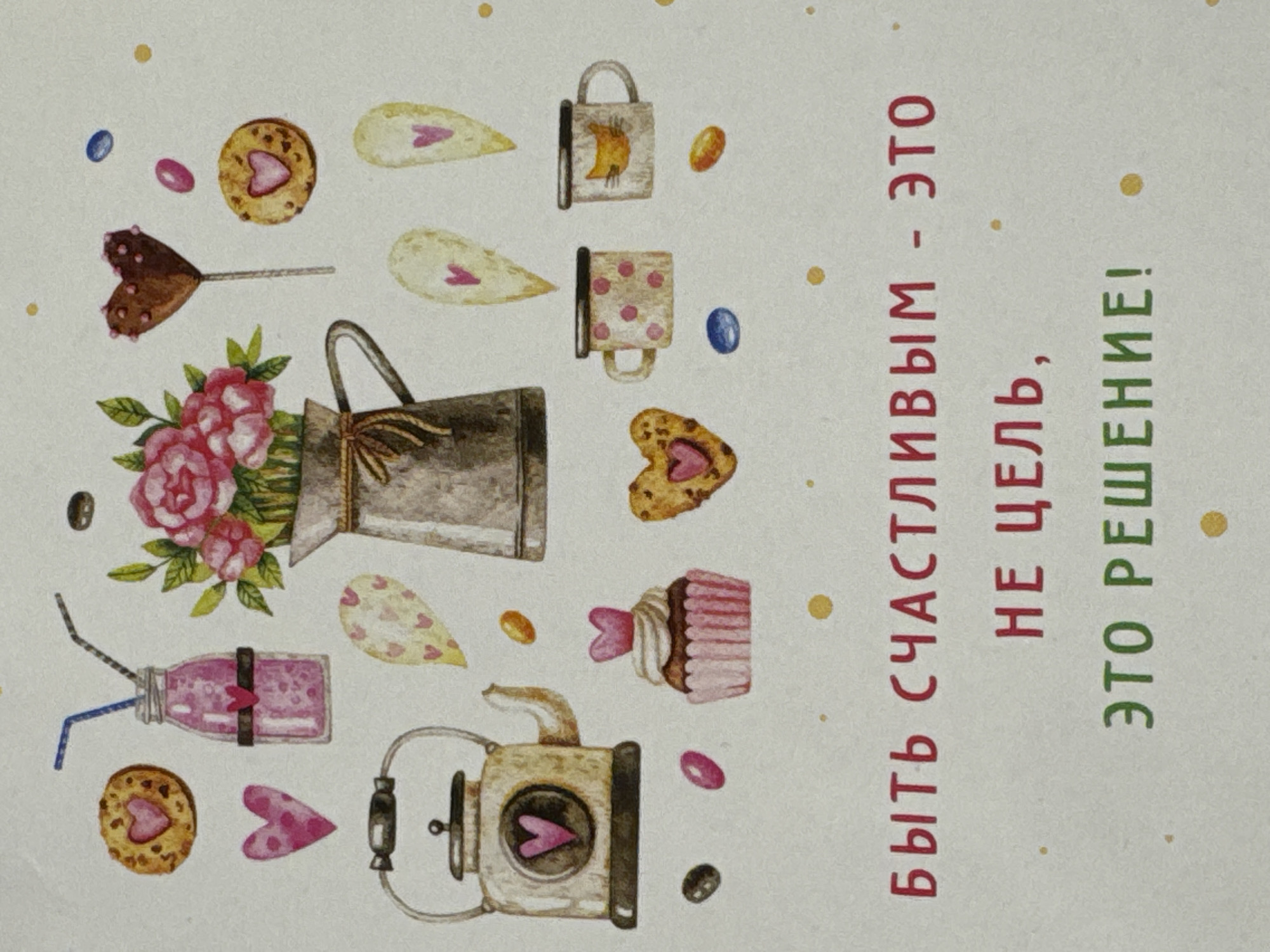 The image shows a postcard with a whimsical design. It features watercolor-style illustrations of various items such as cookies with heart cutouts, a chocolate heart lollipop, a bouquet of roses in a metal pitcher, a pink drink in a jar with straws, a heart-shaped candy, a cupcake with a heart, coffee mugs, and a vintage-looking kettle. The objects are scattered across the card, surrounded by small dots. The postcard also includes Russian text in red and green ink that reads: "Быть счастливым - это не цель, это решение!" which translates to "To be happy is not a goal, it is a decision!". There is no indication of the location of Izhevsk, Russia in the image.