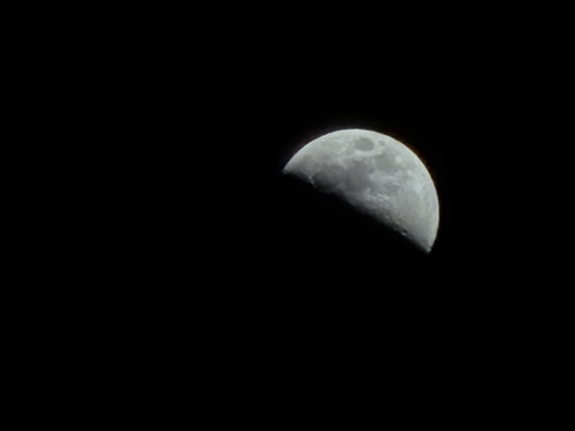 The image depicts a crescent moon against a completely black sky. There are no visible details suggesting a specific location or city like Izhevsk. There are no people, subjects, objects other than the moon, actions, or interactions depicted in the image. The environment is simply a black, starless sky.