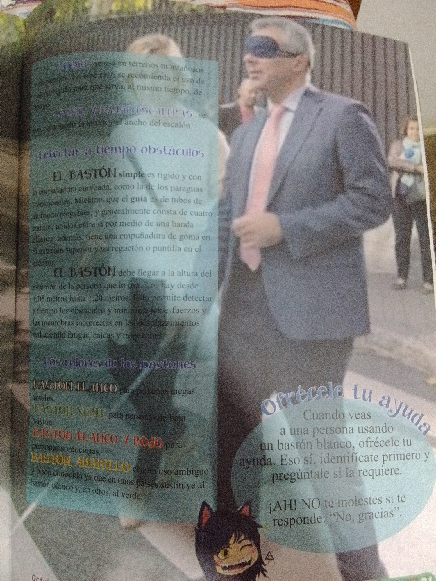 This image is a page from a magazine or book. The foreground features an illustration of a cartoon character with cat ears and fangs, looking mischievous. To the right of the cartoon character is a light blue oval containing text. The main part of the image is a photograph of a man wearing a suit and a blindfold, with a pink tie. He is standing in front of a blurred background of vertical wooden slats, suggesting an indoor setting or a structured outdoor area.
The text on the page discusses different types of canes used by visually impaired and hearing-impaired individuals. It describes the function and length of these canes and provides information on how to offer assistance to someone using a white cane.
The text also mentions "La Tagua, Venezuela." However, there is no visual information within the image that directly depicts or relates to the city of La Tagua, Venezuela. The image is a general illustration and photograph with accompanying text.