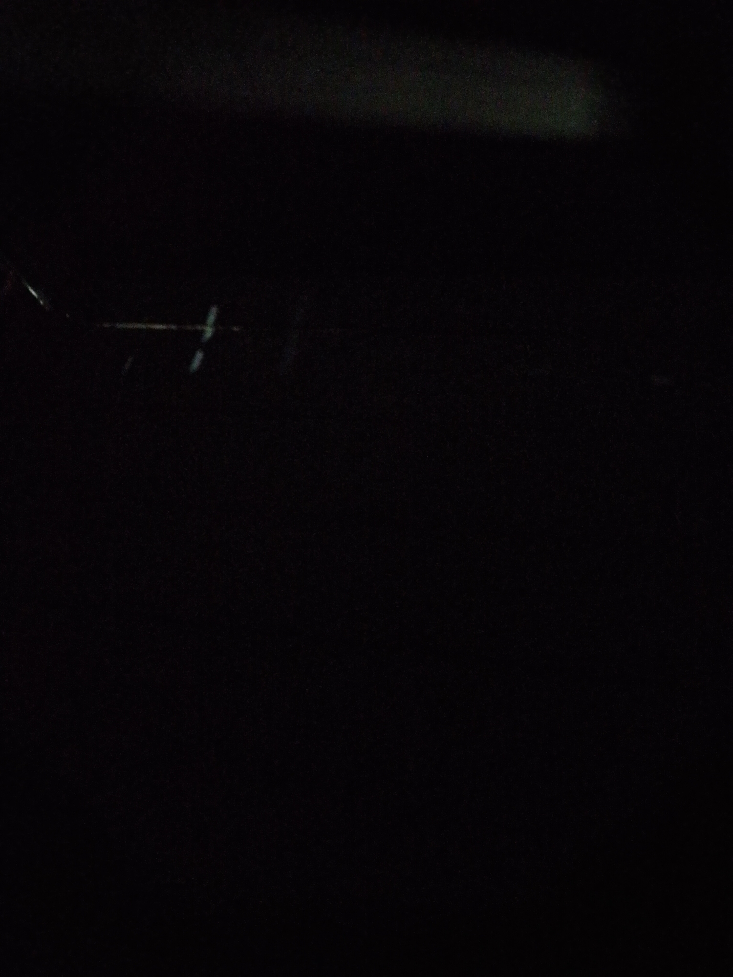The image is extremely dark and indistinct. Faint, linear shapes are visible in the upper portion of the frame, possibly metallic in nature. Due to the lack of light and detail, it is impossible to discern any meaningful information about the location or any other subjects or objects. The specified location in Bukit Ketok, Indonesia, cannot be confirmed or related to the image content.