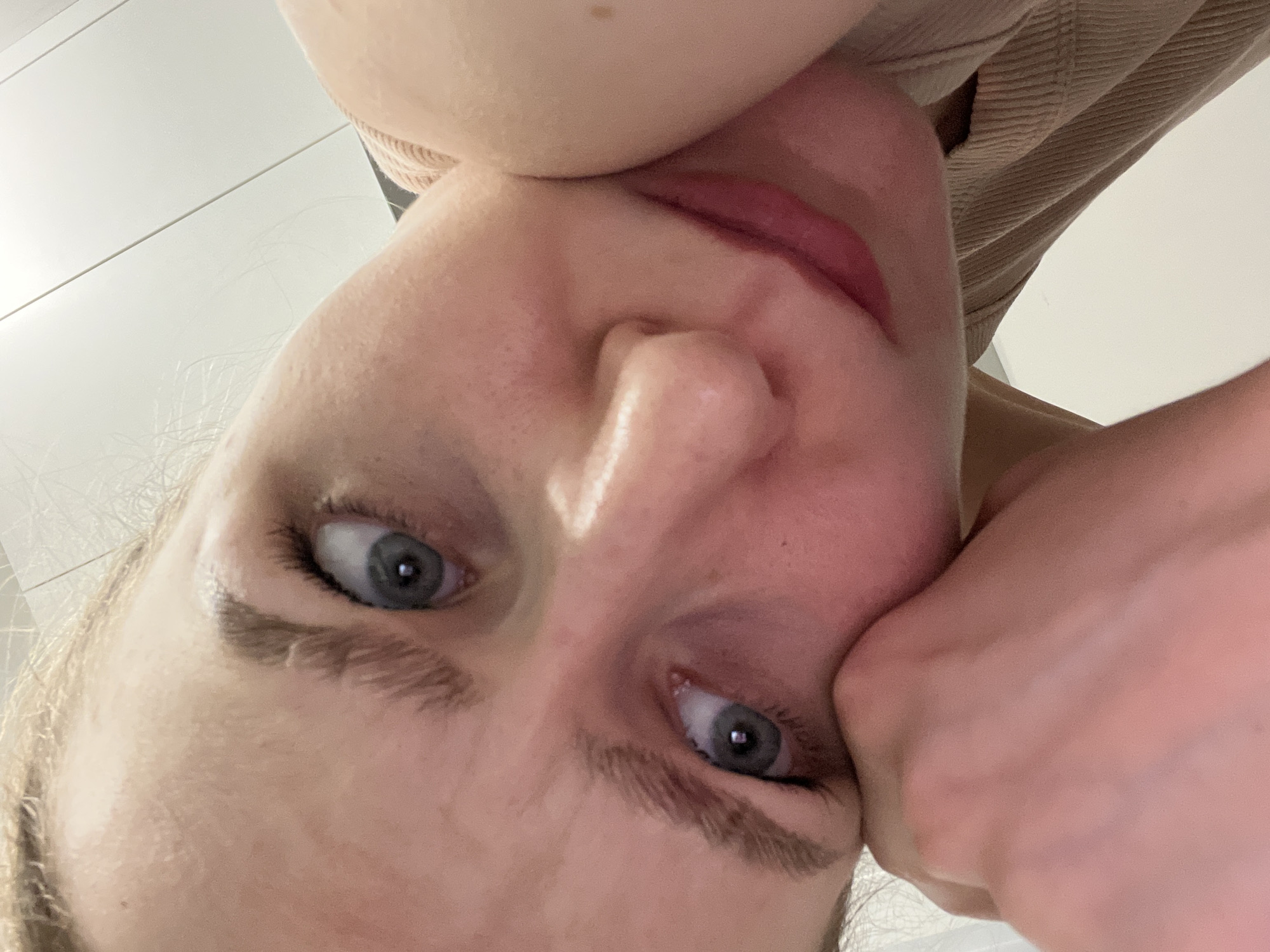 A close-up, upside-down portrait of a fair-skinned person with blue eyes. The person's face is partially obscured by their own hand. They have a fair complexion, and their lips are visible. The background appears to be a neutral color. There is no indication of this image being taken in Khimki, Russia.