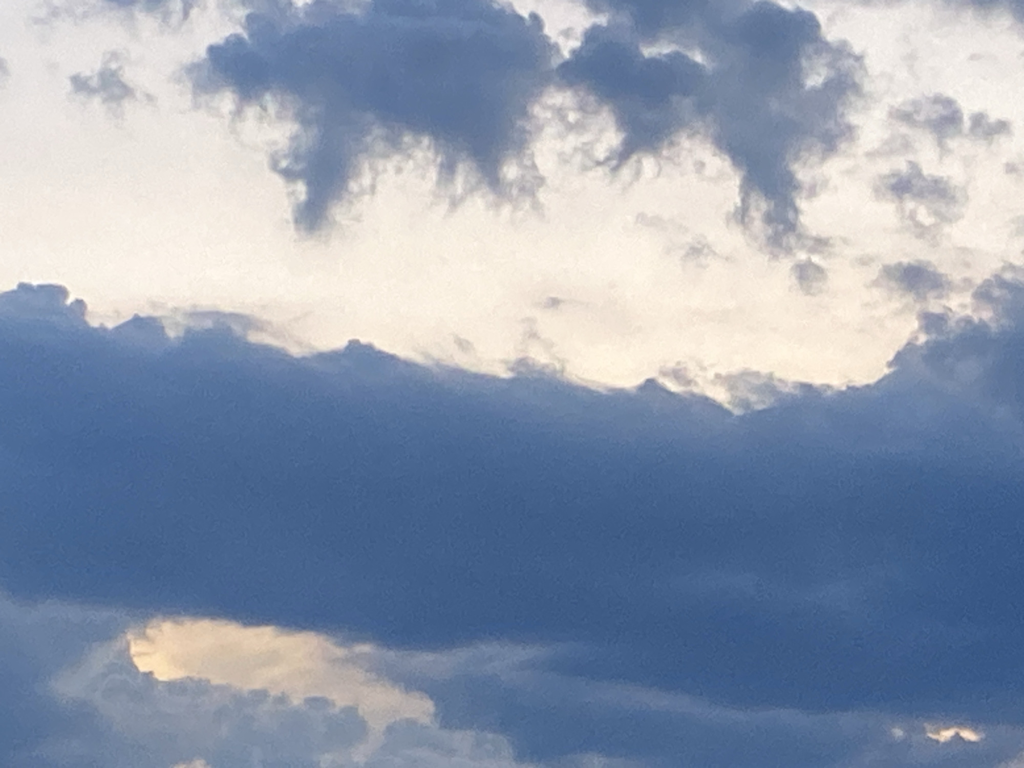 The image shows a view of clouds in the sky. The clouds are primarily dark blue-gray, with some areas of lighter, almost white, sky visible between and behind the darker formations. Some of the cloud formations have distinct shapes and edges. The environment appears to be outdoors, under an overcast or partly cloudy sky. The location of Markovskii, Russia is unknown.