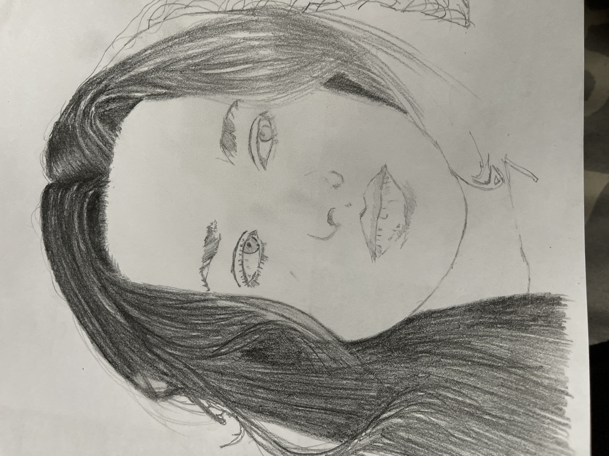 The image is a pencil sketch of a person's face. The person appears to have long, dark hair. The facial features are partially shaded, including the eyes, nose, and lips. The drawing is on white paper. The drawing is angled. The city of Jos, Nigeria, is not apparent in the image.