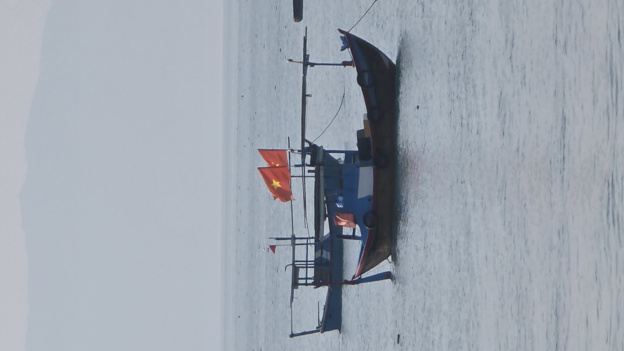 A boat with Vietnamese flags is on the water near Bắc Nha Trang, Vietnam.