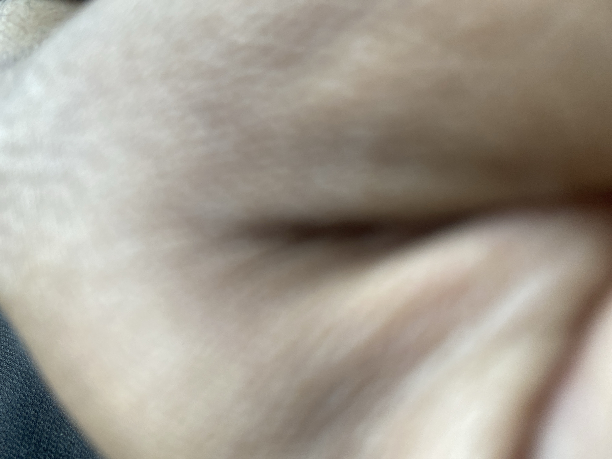 The image appears to be a highly out-of-focus close-up of human skin, possibly an eyelid, with a blurred dark line suggesting eyelashes. A section of denim fabric is visible on the left side of the frame. Due to the extreme blur and lack of context, no information related to the city of Bukhara, Uzbekistan, is discernible.