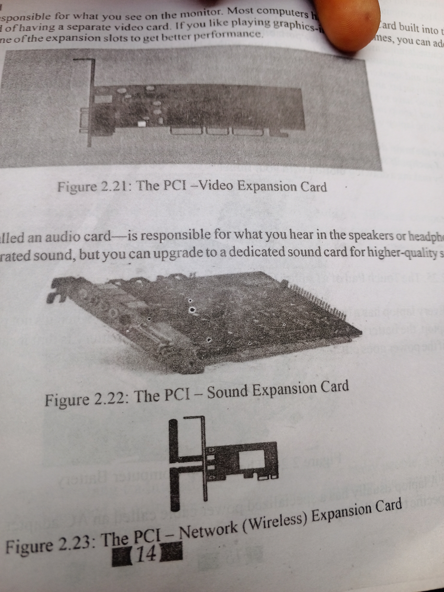 This media file is a close-up photograph of a page from a textbook or manual, displaying text and images related to computer hardware.
The primary subjects are the printed content on the page and a small portion of a person's thumb, which is visible at the top right, suggesting someone is holding or turning the page. The objects depicted are illustrations of computer expansion cards: a video card (Figure 2.21), a sound card (Figure 2.22), and a network card (Figure 2.23). These images are black and white line drawings or grayscale photographs.
The text discusses the function of these expansion cards, explaining that a video card is responsible for displaying images on the monitor and can be upgraded for better graphics performance. An audio card's role in producing sound is also described, with the option to upgrade for higher-quality audio. The text is presented in English.
The setting appears to be indoors, likely in a place where one would study or work with educational materials. There are no specific time of day or weather cues. The location context provided states Jalingo, Nigeria, but this cannot be inferred from the image itself. The visible text includes captions for the figures, such as "Figure 2.21: The PCI - Video Expansion Card," and descriptive sentences about the components. There is also a partially obscured number "14" below Figure 2.23. No emotions are conveyed as the focus is on informational content.