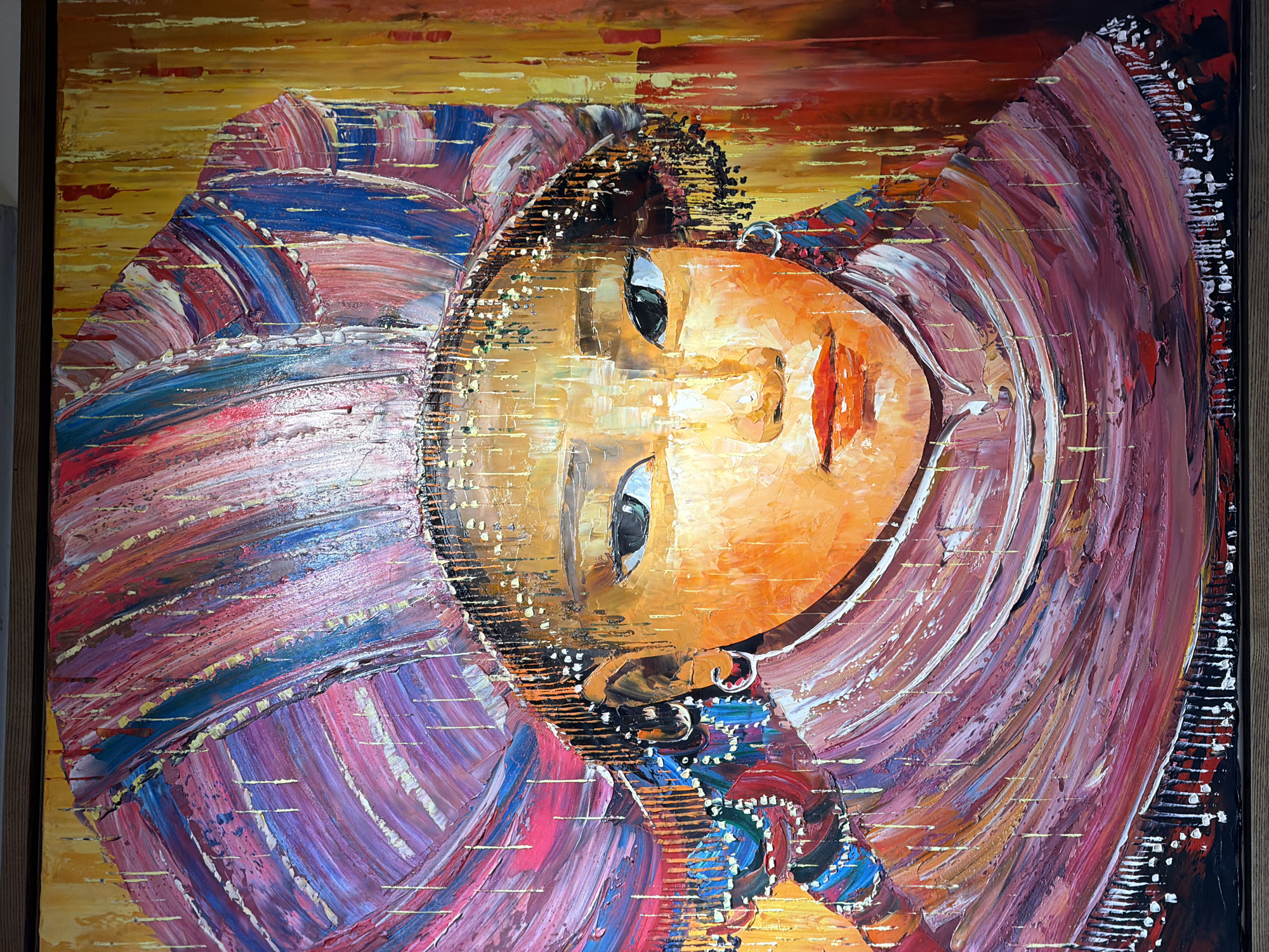 The image shows an oil painting of a young girl with an orange face and dark eyes. She is wearing a head covering with brushstrokes of pink, purple, red, and blue. The background is a blend of orange and yellow. The painting is framed.