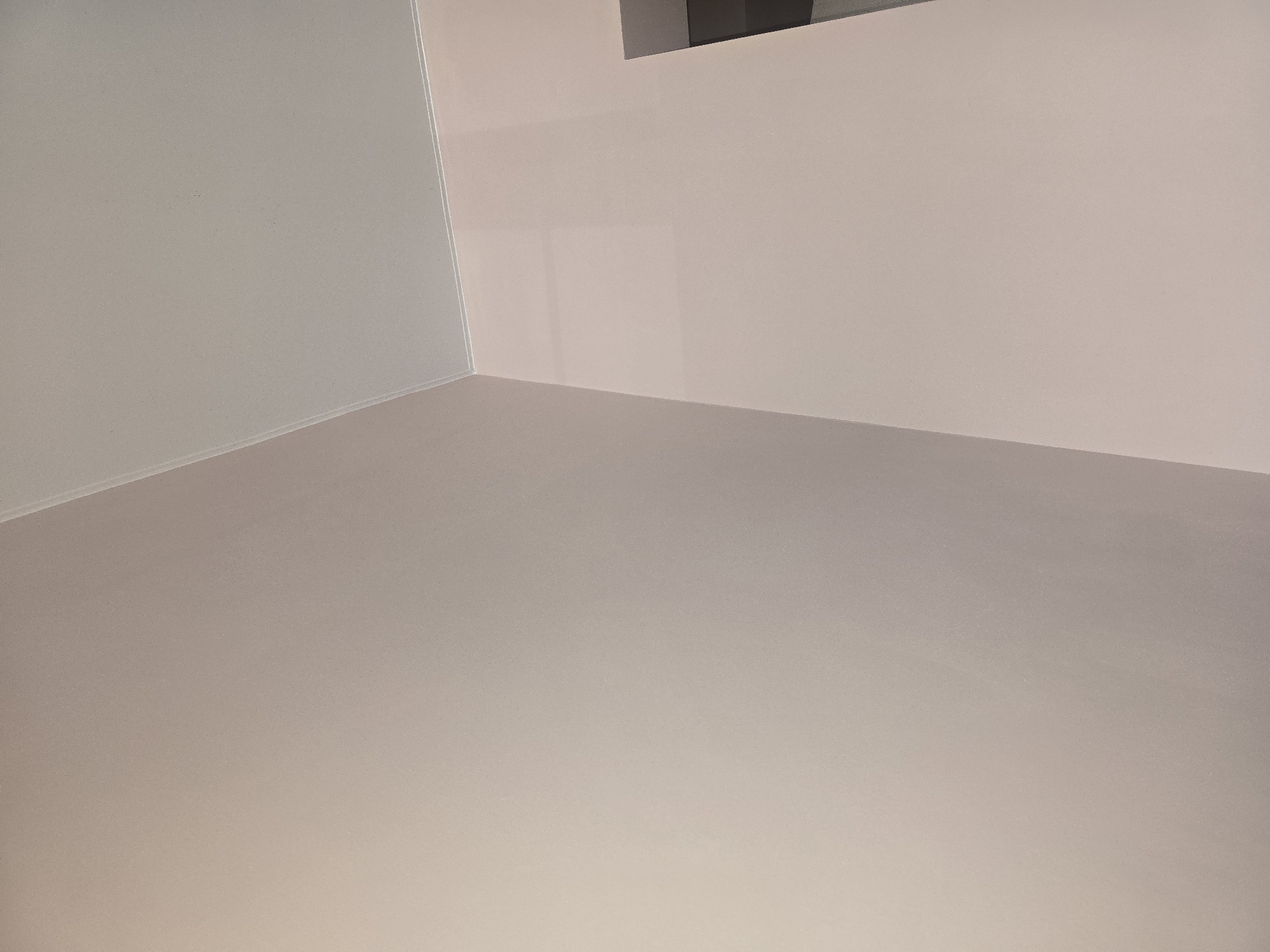 The image shows an interior view of a room, focusing on the corner where two walls meet the ceiling. The walls are painted a pale pink color, and the ceiling is a light grey. The lighting suggests it is daytime, but the specific location within Ulan-Ude, Russia, cannot be determined from the visual information provided. There are no people or specific objects visible that would indicate a particular purpose or activity within the room. The scene is clean and appears to be a residential or office space.
