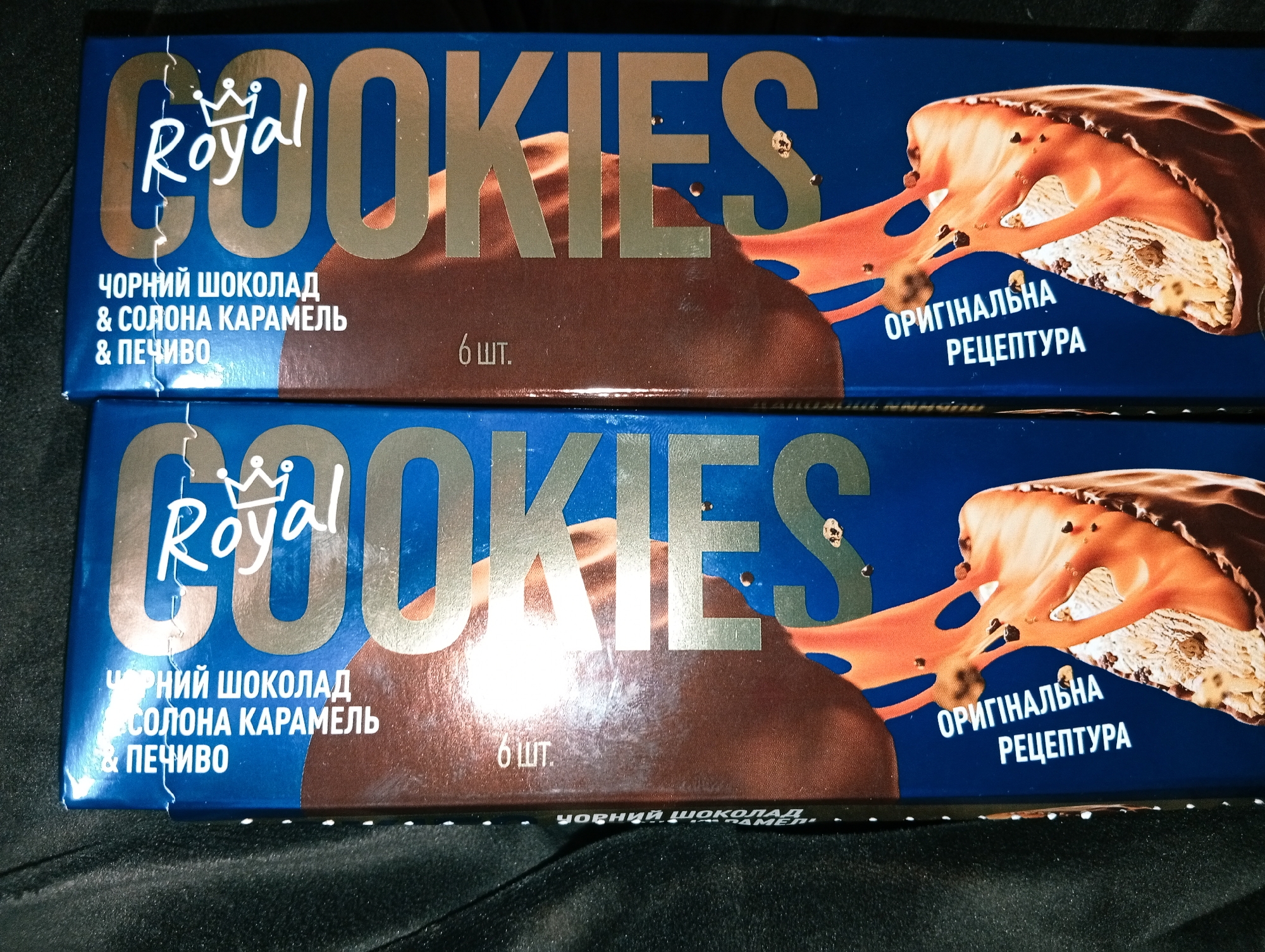 The image shows two packages of Royal Cookies. The boxes are blue with gold lettering and an image of a cookie with chocolate and caramel. The text on the boxes is in Ukrainian. It states the cookies are "Black chocolate & salted caramel & biscuits." The boxes also state "6 pcs." and "Original recipe."