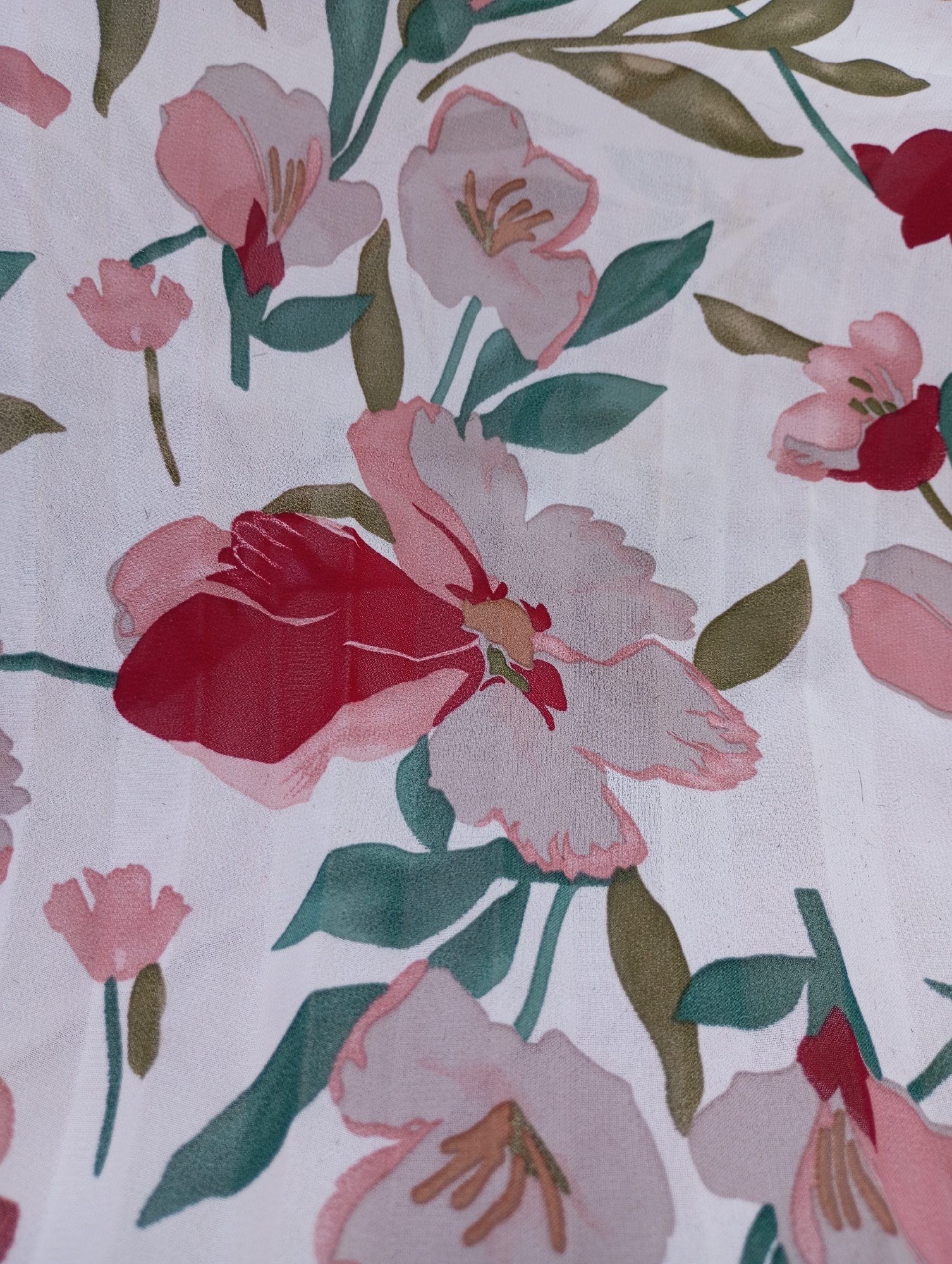 The image shows a close-up of a fabric with a floral pattern. The background is white, and the pattern consists of flowers and leaves. The flowers are rendered in shades of pink and red, with some having a darker red accent. The leaves are green and brown. There is no indication of the city of Izhevsk, Russia, in the image.