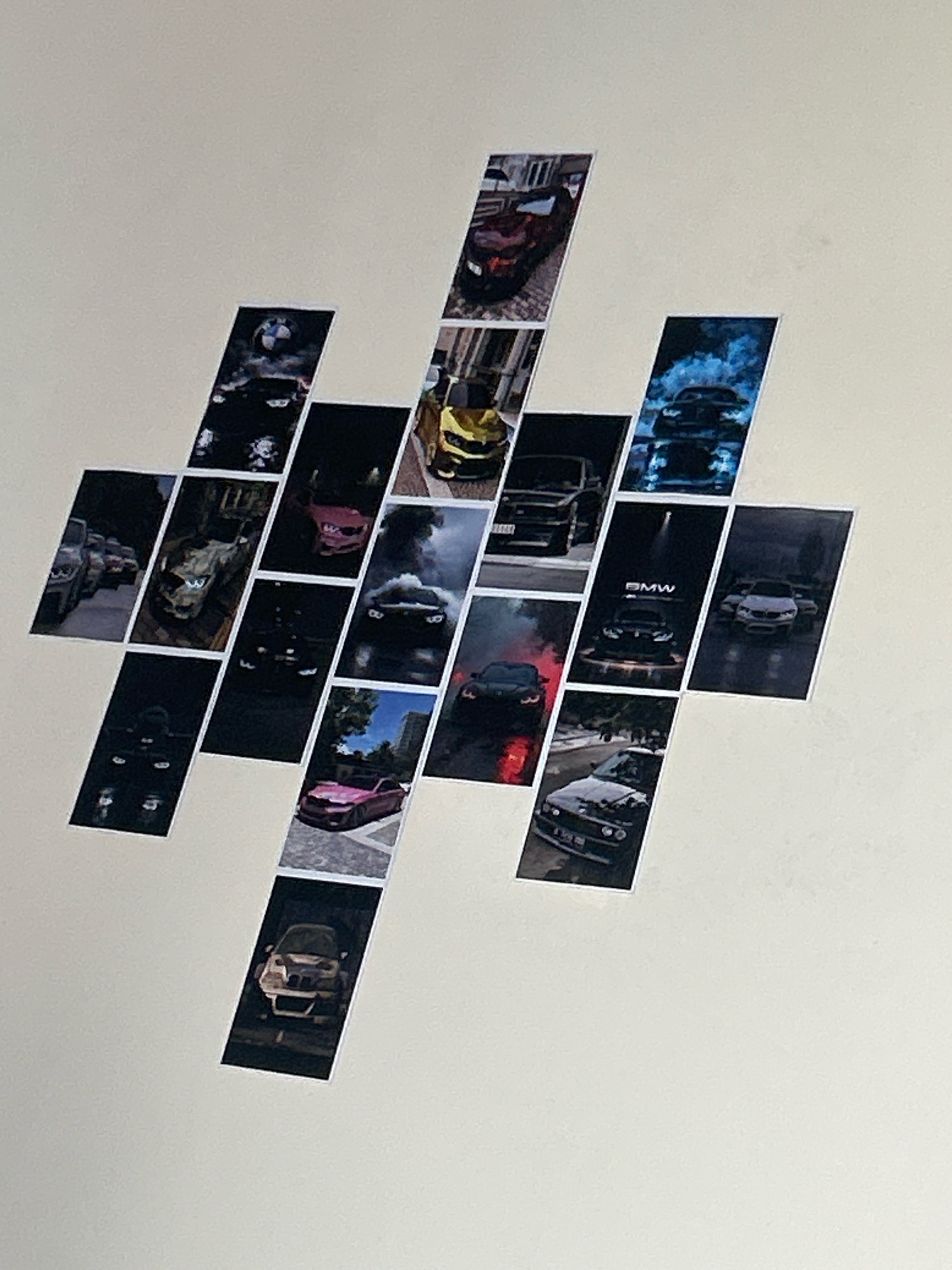The image displays a wall with a collage of photographs featuring cars. The photographs are arranged in a staggered pattern, resembling a diamond shape. The cars depicted in the photographs include various models, some of which appear to be luxury or performance vehicles. The collage is adhered to a plain, off-white wall. There is no indication of the city of Bhopal, India, in the image or its context.