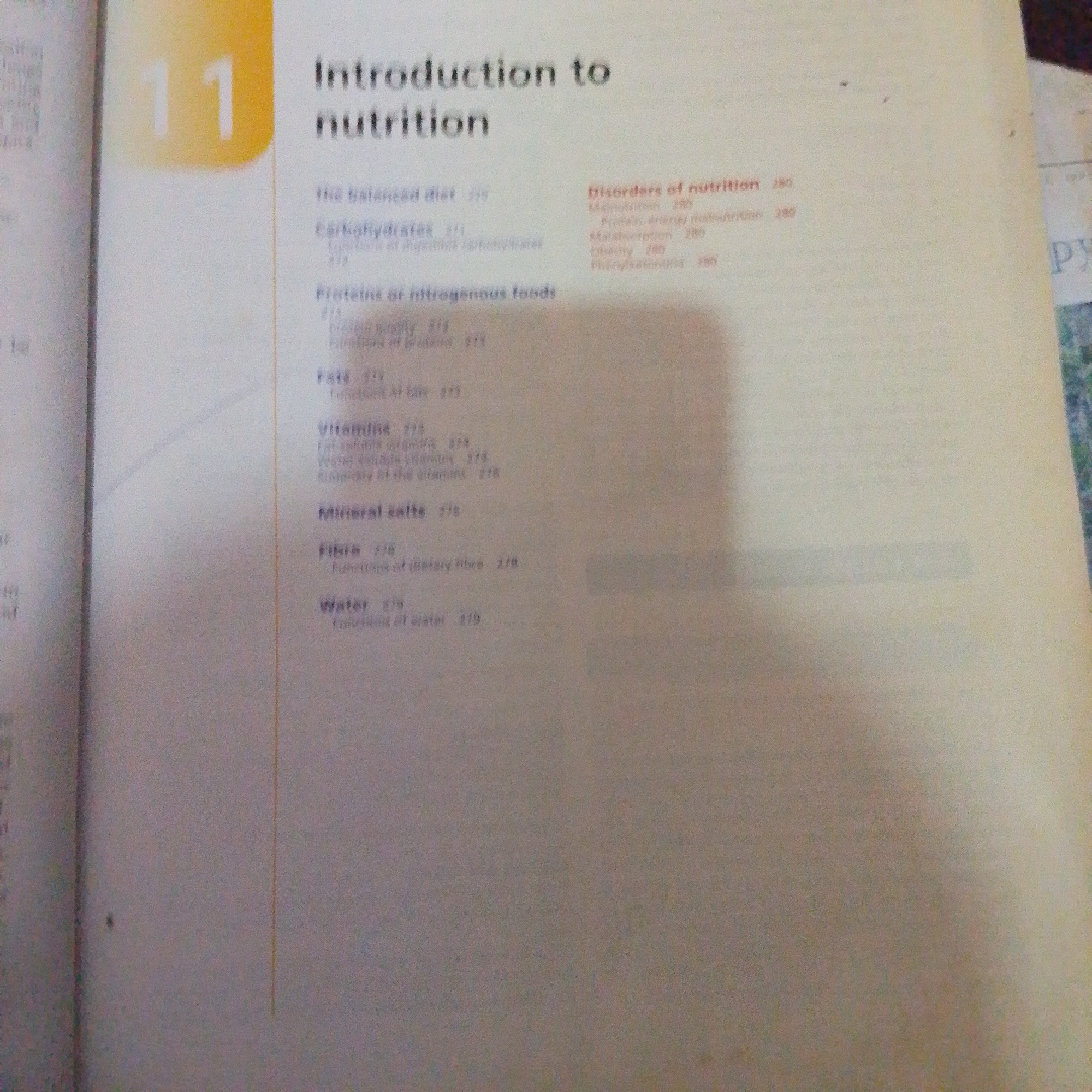 The image shows a page from a textbook with the chapter title "Introduction to nutrition" and a chapter number "11". The page contains a table of contents or index with various nutritional topics and their corresponding page numbers. Some of the listed topics include "The balanced diet", "Carbohydrates", "Proteins or nitrogenous foods", "Fats", "Vitamins", "Mineral salts", "Fibre", and "Water". On the right side of the page, there is a section titled "Disorders of nutrition" with subtopics such as "Malnutrition", "Protein-energy malnutrition", "Malabsorption", "Obesity", and "Phenylketonuria". The text is clear and legible, indicating a well-printed book. The background is a plain, light-colored paper, typical of a book page. There are no indications of the city of Jalingo, Nigeria, or any environmental elements that would suggest a specific geographic location. The image is a close-up view of the book page, with no surrounding context visible.