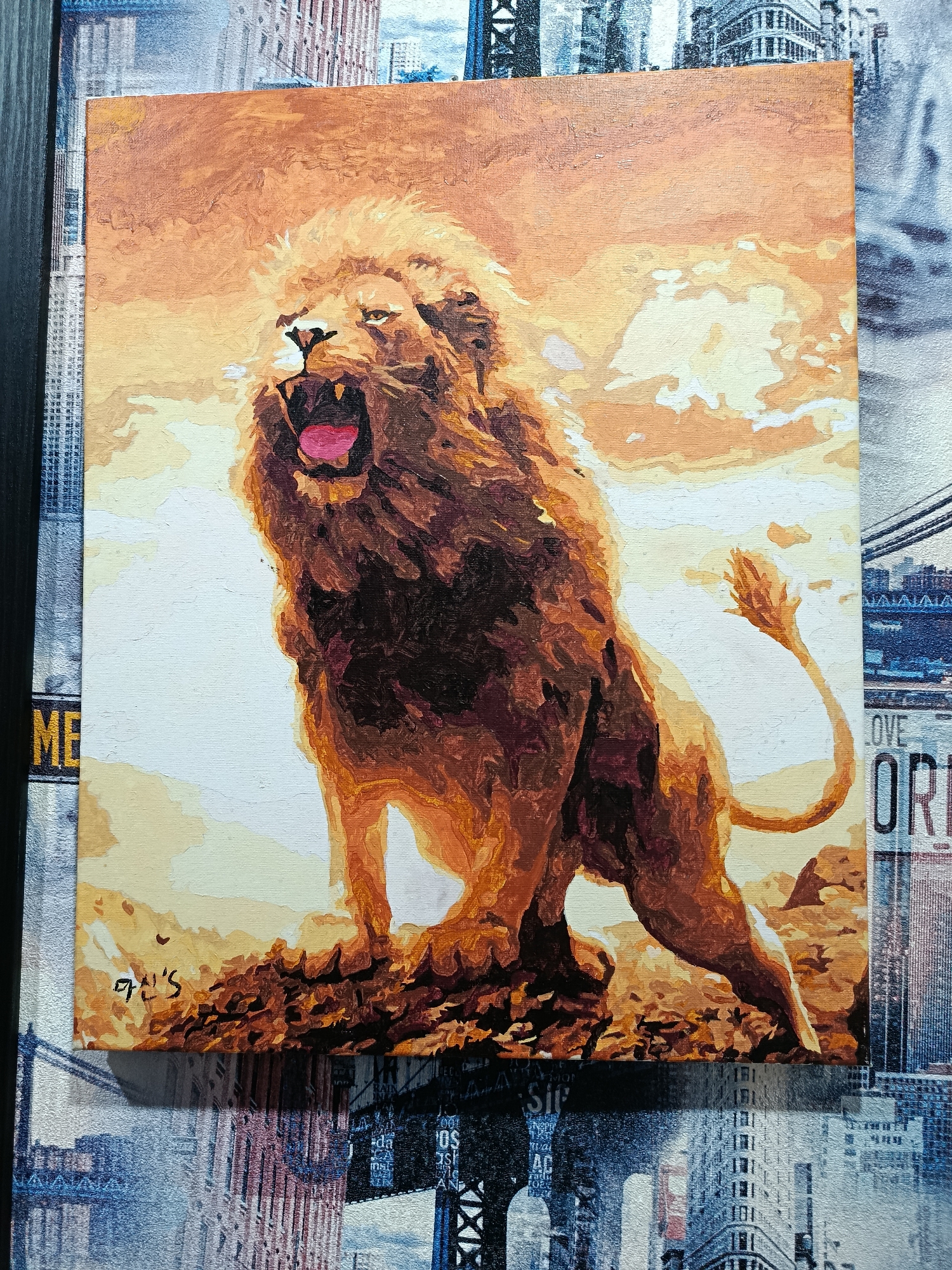 This is a photograph of a painting of a roaring lion standing on a rocky outcrop against a backdrop of a warm, cloudy sky. The lion's mouth is open, revealing its pink tongue and teeth. Its mane is prominent and flowing. The painting is set on top of what appears to be a collage of images of cityscapes and street signs, including a sign that reads "LOVE OR I". The lower portion of the collage shows a cityscape with bridges and tall buildings. The painting is signed in the lower left corner with what appears to be Korean script. There is no information in the image to suggest any connection to Apatity, Russia.