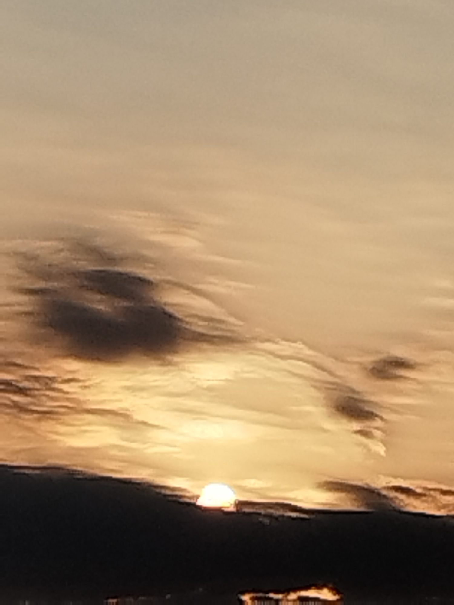 This is a photograph of a sunset over the city of Vidra, Romania. The sky is filled with clouds that are lit by the setting sun, creating a warm, golden glow. In the foreground, a dark silhouette of buildings can be seen against the bright sky. The overall impression is one of peace and tranquility.