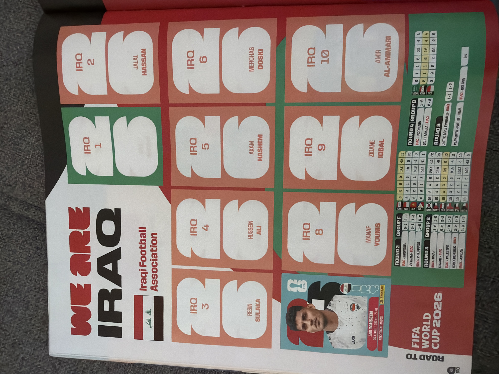 The image shows a page from a sticker album, likely related to the FIFA World Cup 2026, with a focus on the Iraqi national football team.
The prominent elements are:
- The text "WE ARE IRAQ" in large, bold, red letters.
- The word "IRAQ" in large, bold, black letters below the red text.
- An Iraqi flag with the text "الله اكبر" (Allahu Akbar).
- The text "Iraqi Football Association".
- Several large numbered cutouts with "IRQ" followed by a number (1 through 10). Some of these cutouts also contain the names of players, such as JALAL HASSAN, REBIN SULAKA, HUSSEIN ALI, AKAM HASHEM, MERCHAS DOSKI, MANAF YOUNIS, ZIDANE IQBAL, and AMIR AL-AMMARI. One cutout features a portrait of a footballer identified as ZAID TAHSEEN, with his details (29-1-2001, 1.93 m, 77 kg) and a club affiliation (PAKH TAKOR FC (UZBE)).
- A section labeled "ROAD TO FIFA WORLD CUP 2026".
- Several tables showing match results and group standings for different rounds (ROUND 2, ROUND 3, ROUND 4 GROUP B, ROUND 5, PLAY-OFFS - PATH B - FINAL). These tables list various countries like INDONESIA, VIETNAM, PHILIPPINES, OMAN, KUWAIT, SOUTH KOREA, JORDAN, SAUDI ARABIA, UNITED ARAB EMIRATES, and BOLIVIA, along with scores and group details.
The image is a close-up of a printed page, possibly a magazine or a dedicated sticker album spread. The background appears to be a textured surface, possibly fabric, suggesting the page is laid out on a surface.
There is no information about Zlatitrap, Bulgaria, in this image. The content exclusively relates to football and the Iraqi national team.