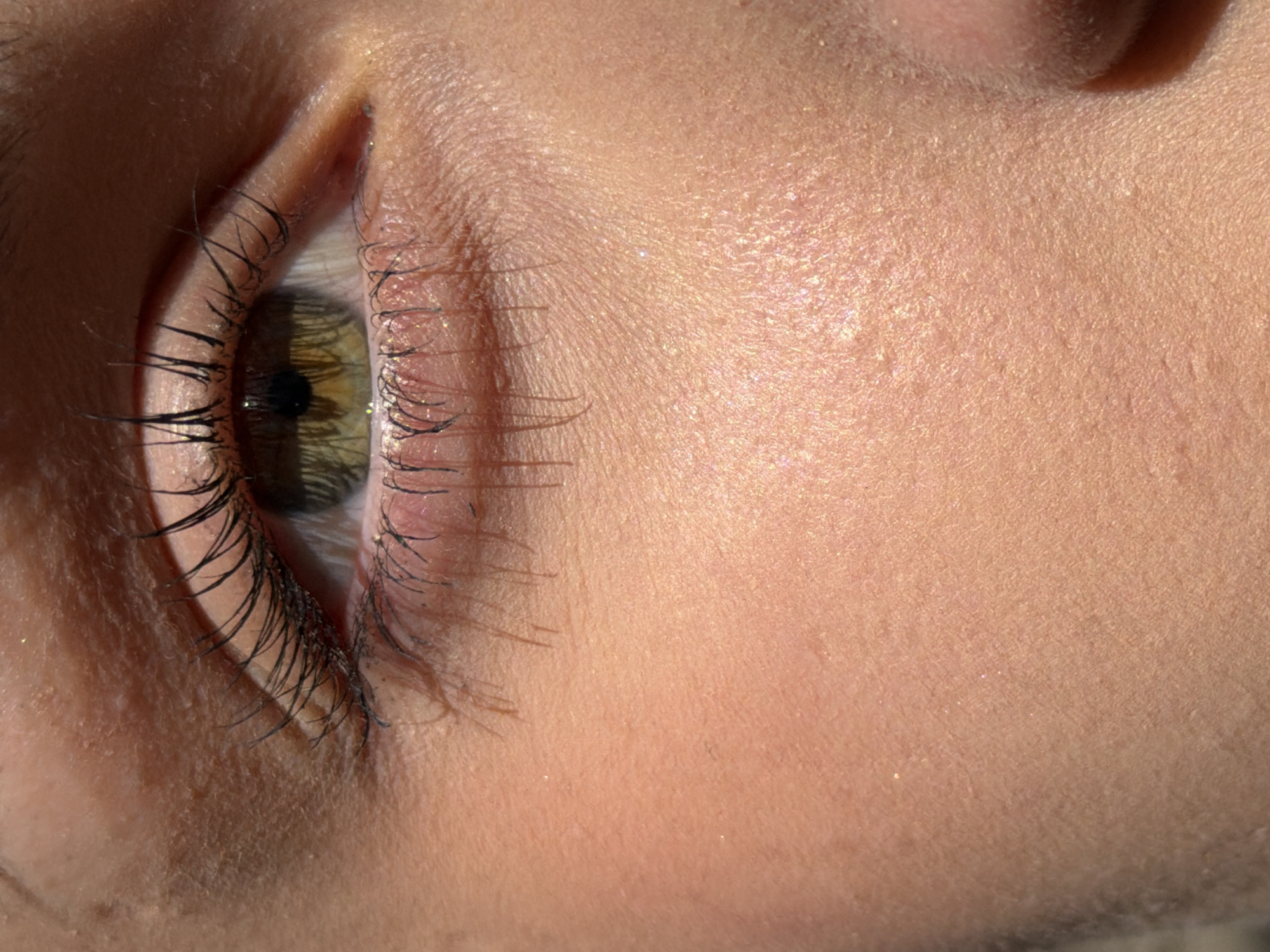 Close-up view of a person's right eye and adjacent facial skin. The eye has green and brown iris and long, dark eyelashes. The skin exhibits fine texture and subtle coloration. Light and shadow play across the face. There is no information in the image about the city of Sofia, Bulgaria.