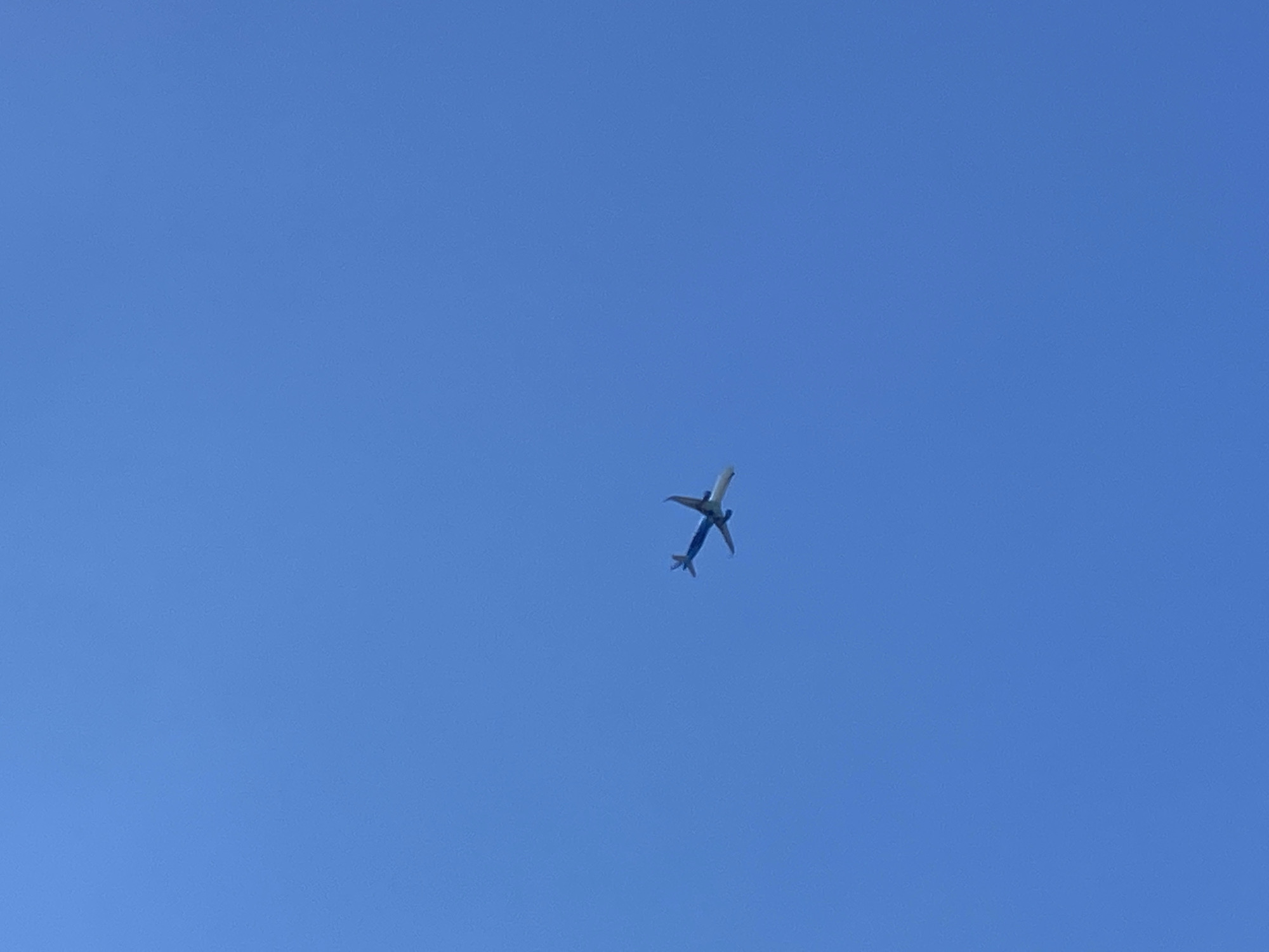 An airplane is flying in the bright blue sky. The airplane appears to be a commercial jet with its wings extended and its body visible against the clear sky. The image does not provide enough information to determine its specific location in Prijevor, Montenegro, or any details about people, actions, or interactions. The environment is simply the open sky.